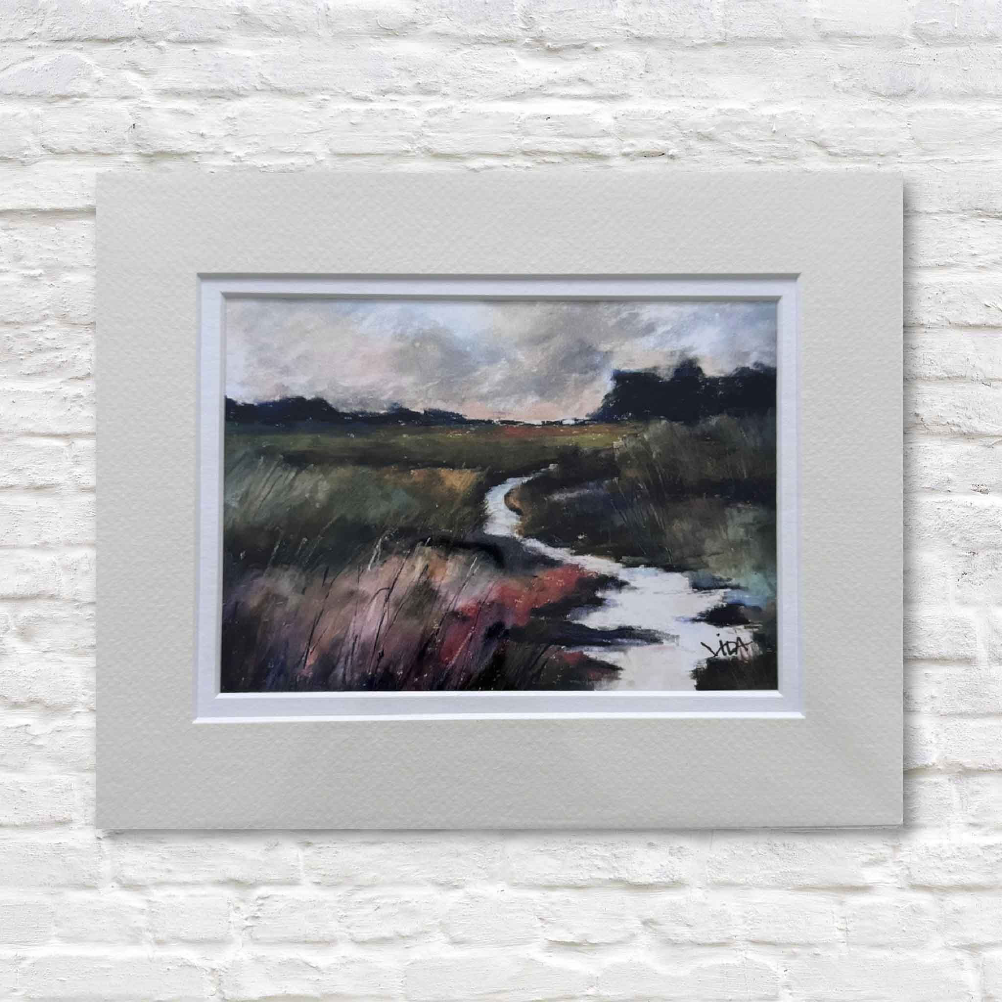 Framed painting of a landscape with a road on a white brick wall
