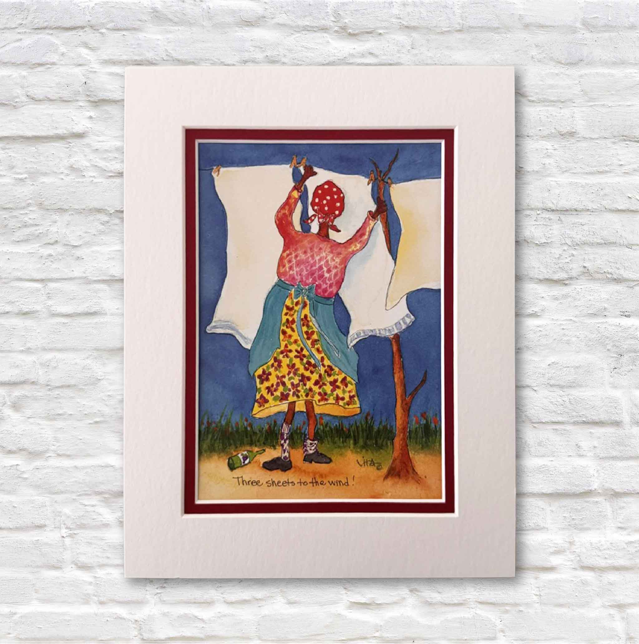matted artwork of a woman hanging clothes on a line against a blue sky.