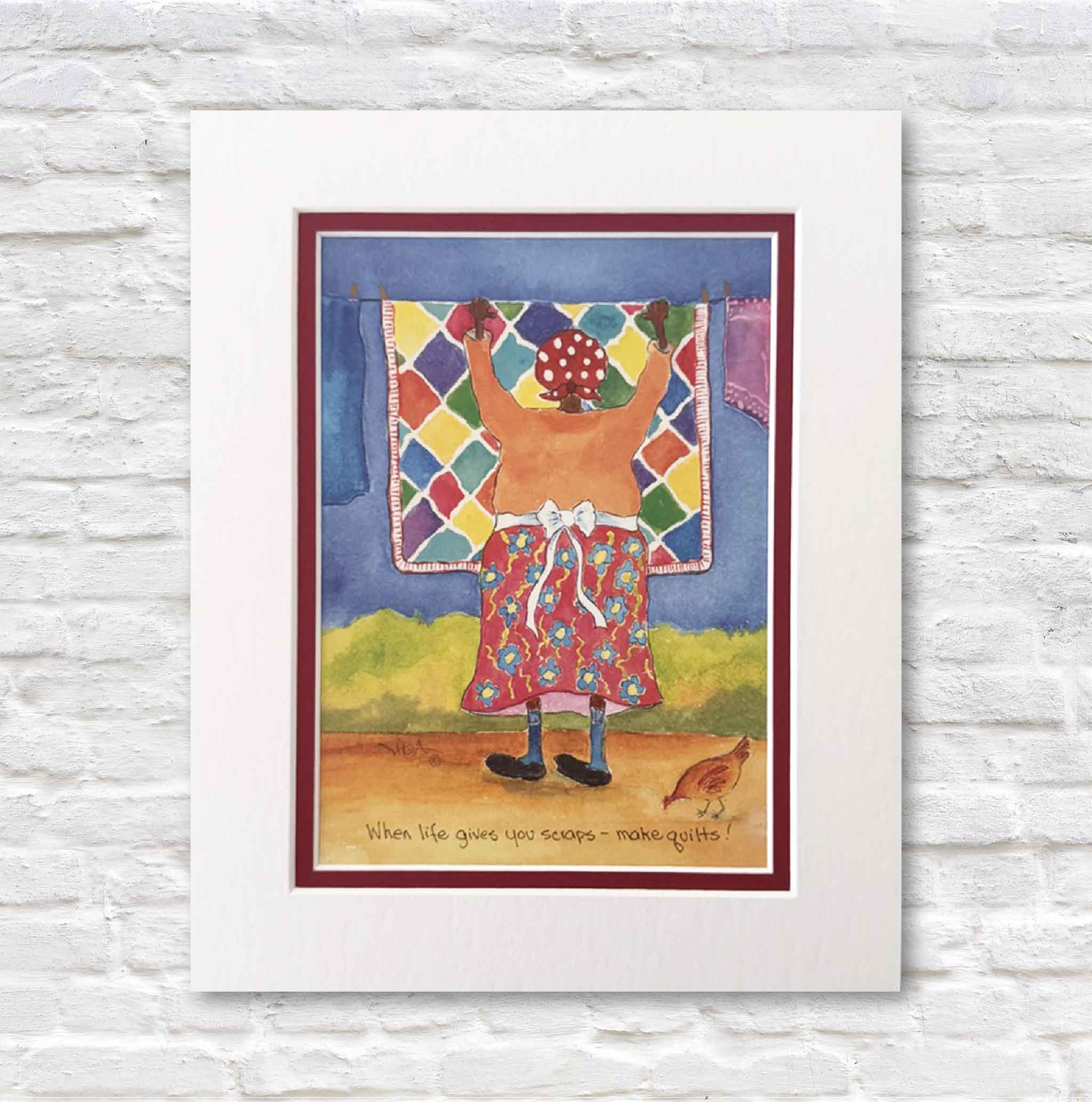 Matted artwork of a person holding a colorful quilt on a white wall.
