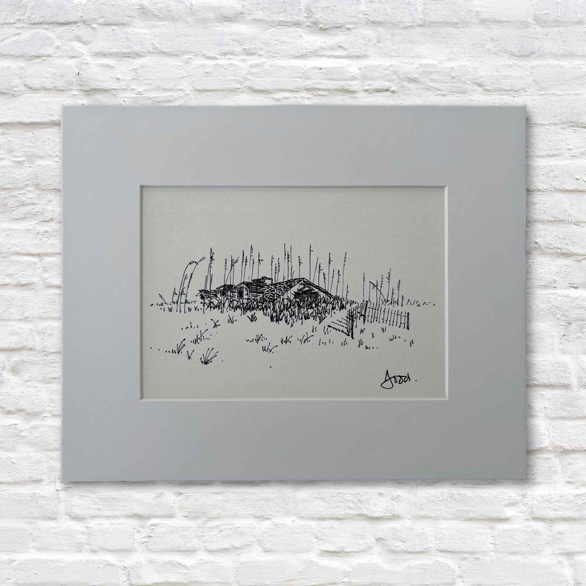 matted black and white drawing of a beach scene with a hut on a white brick wall.
