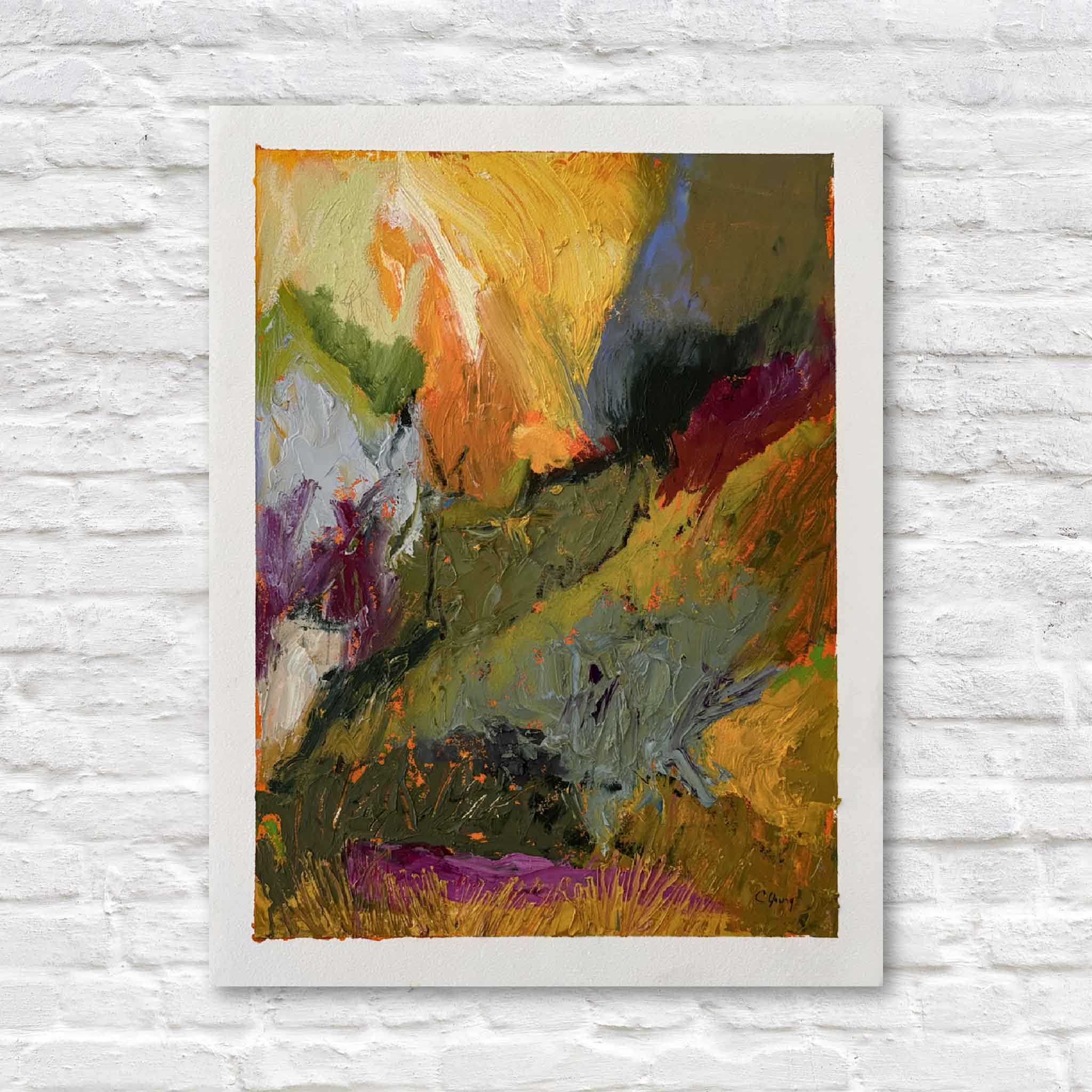 Abstract painting with vibrant colors in a white frame on a textured white wall.