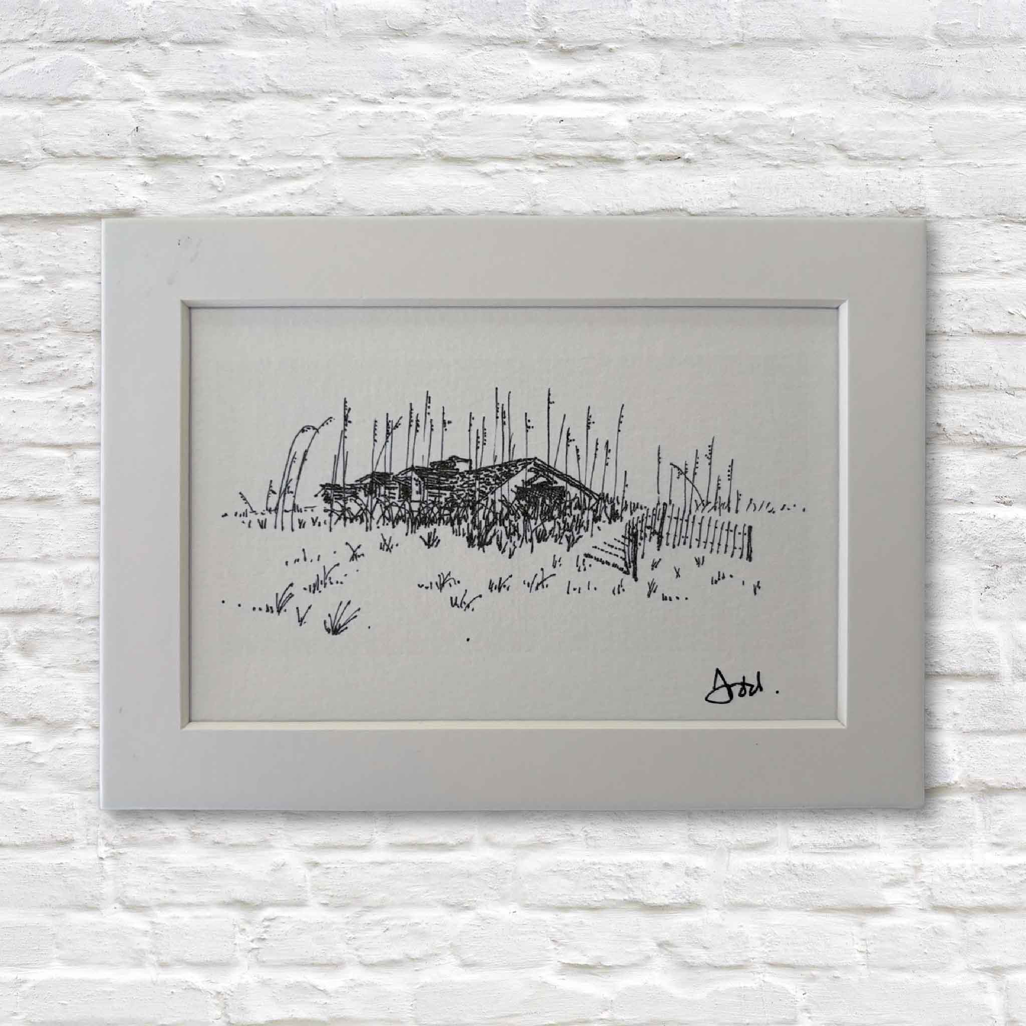 matted black and white drawing of a landscape with a small building on a textured white wall.