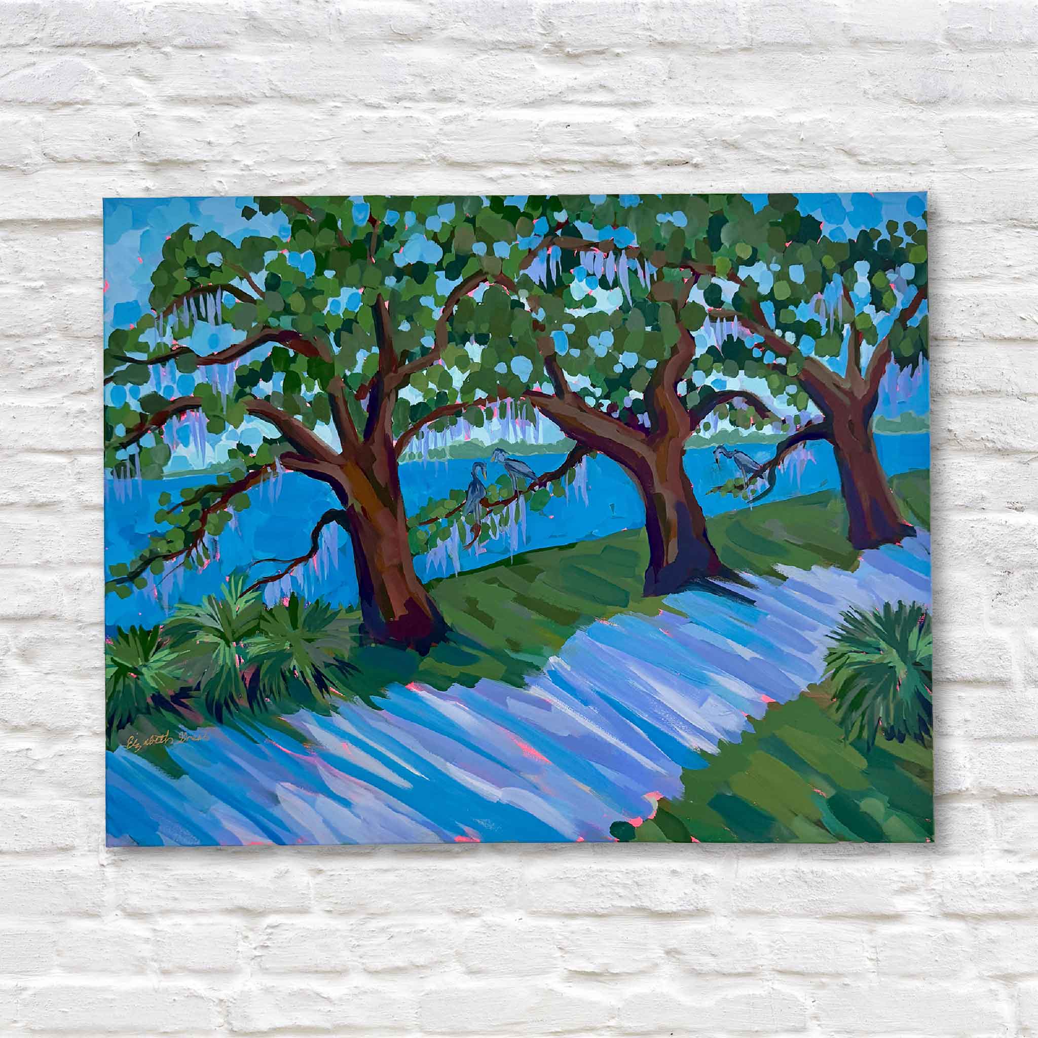Colorful mixed media artwork of lowcountry trees and water against a white brick wall