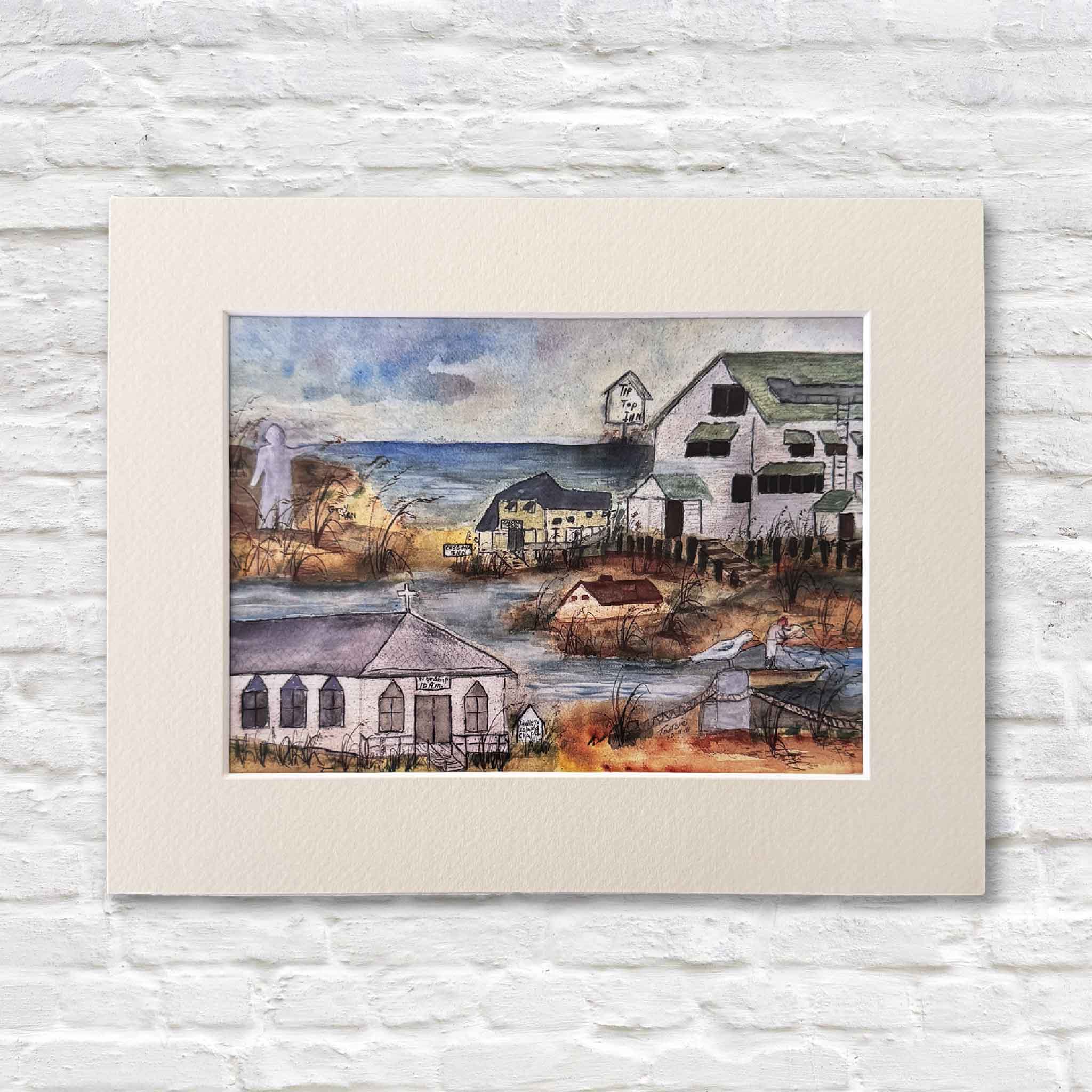 matted artwork of a coastal scene with houses and boats on a white brick wall.