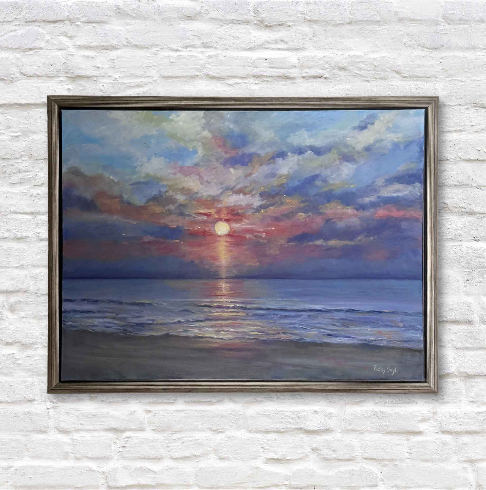 Framed painting of a sunrise over  the ocean on a white brick wall