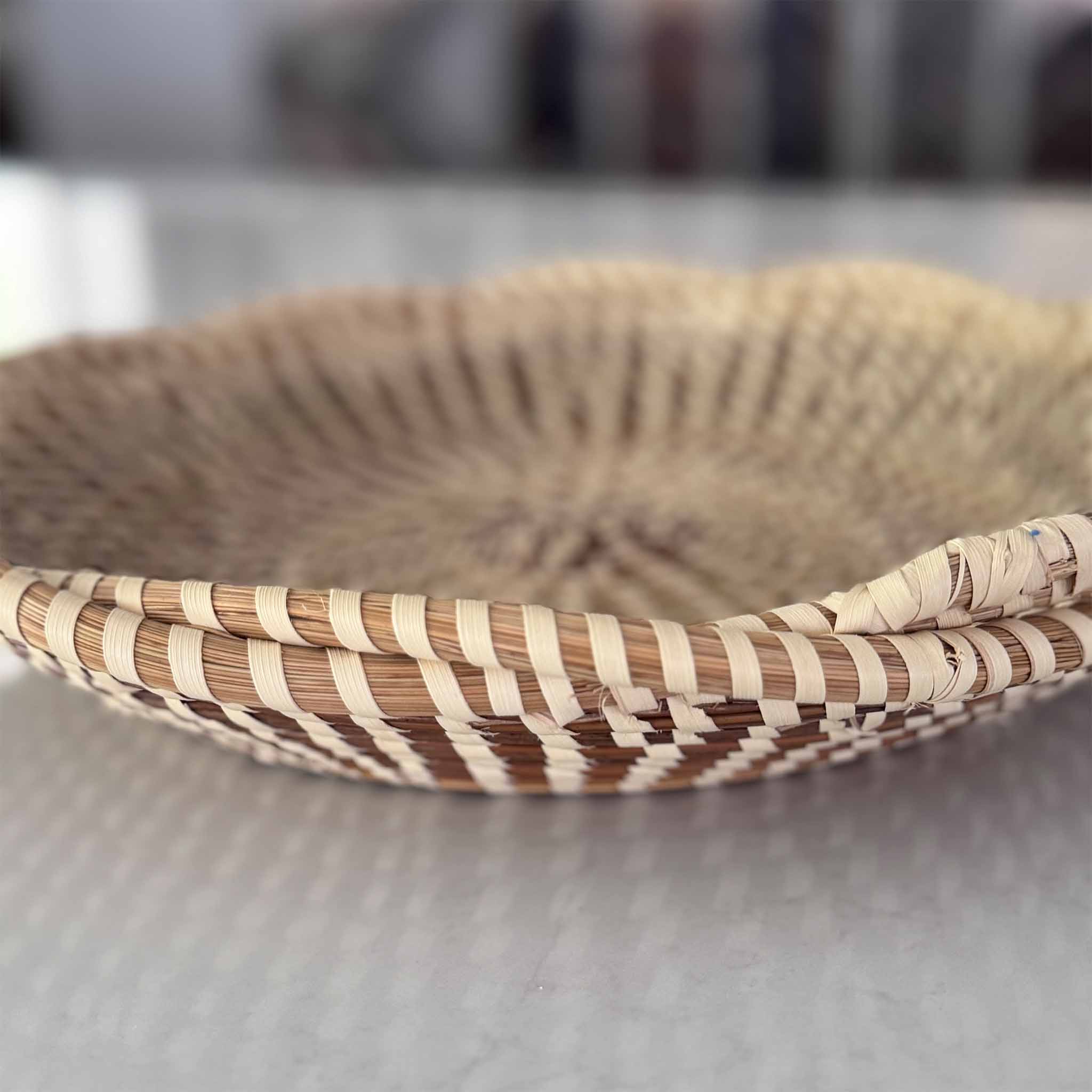 Woven Charleston sweetgrass basket with striped pattern on a gray surface