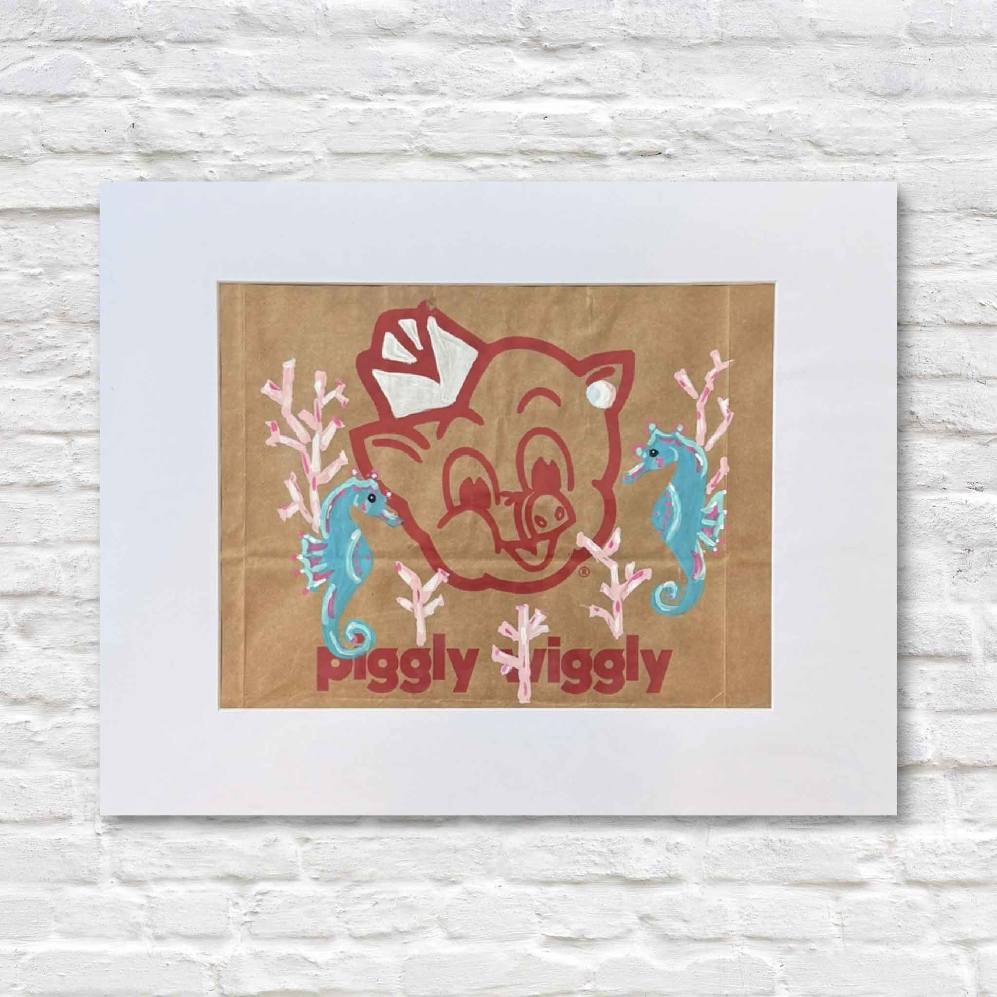 Matted artwork with a cartoon pig design and text 'Piggly Wiggly' on a wooden background