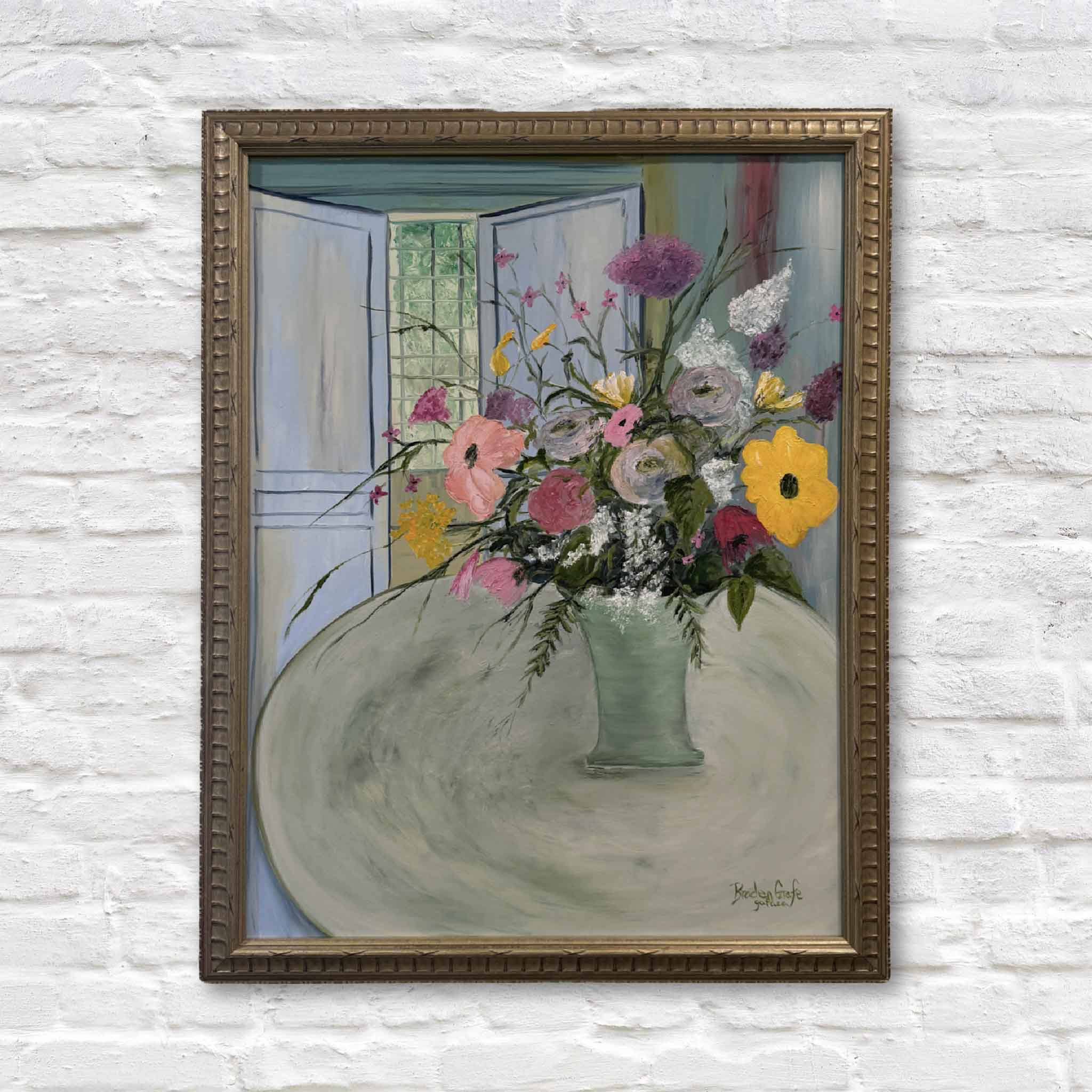 Framed painting of a bouquet of flowers on a white brick wall