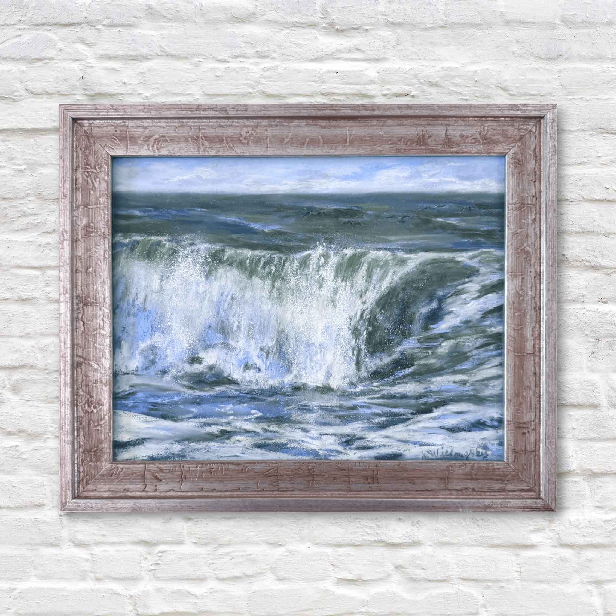Framed painting of a wave crashing against a rocky shore on a white brick wall.