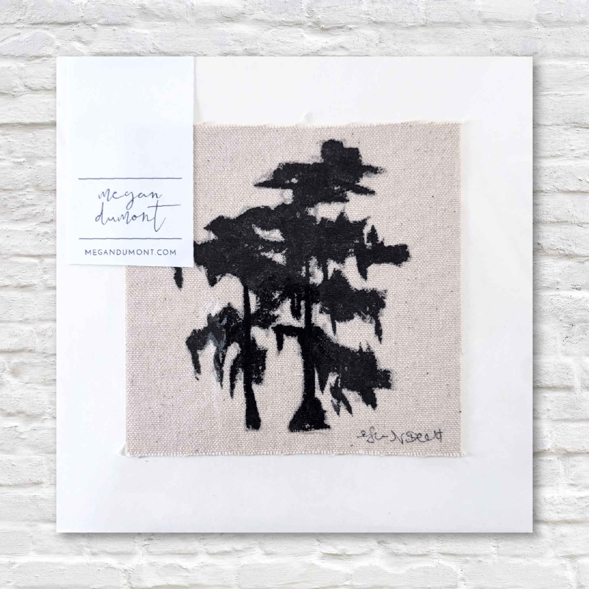 Black tree silhouette on beige fabric with 'Megan Dumont' branding.