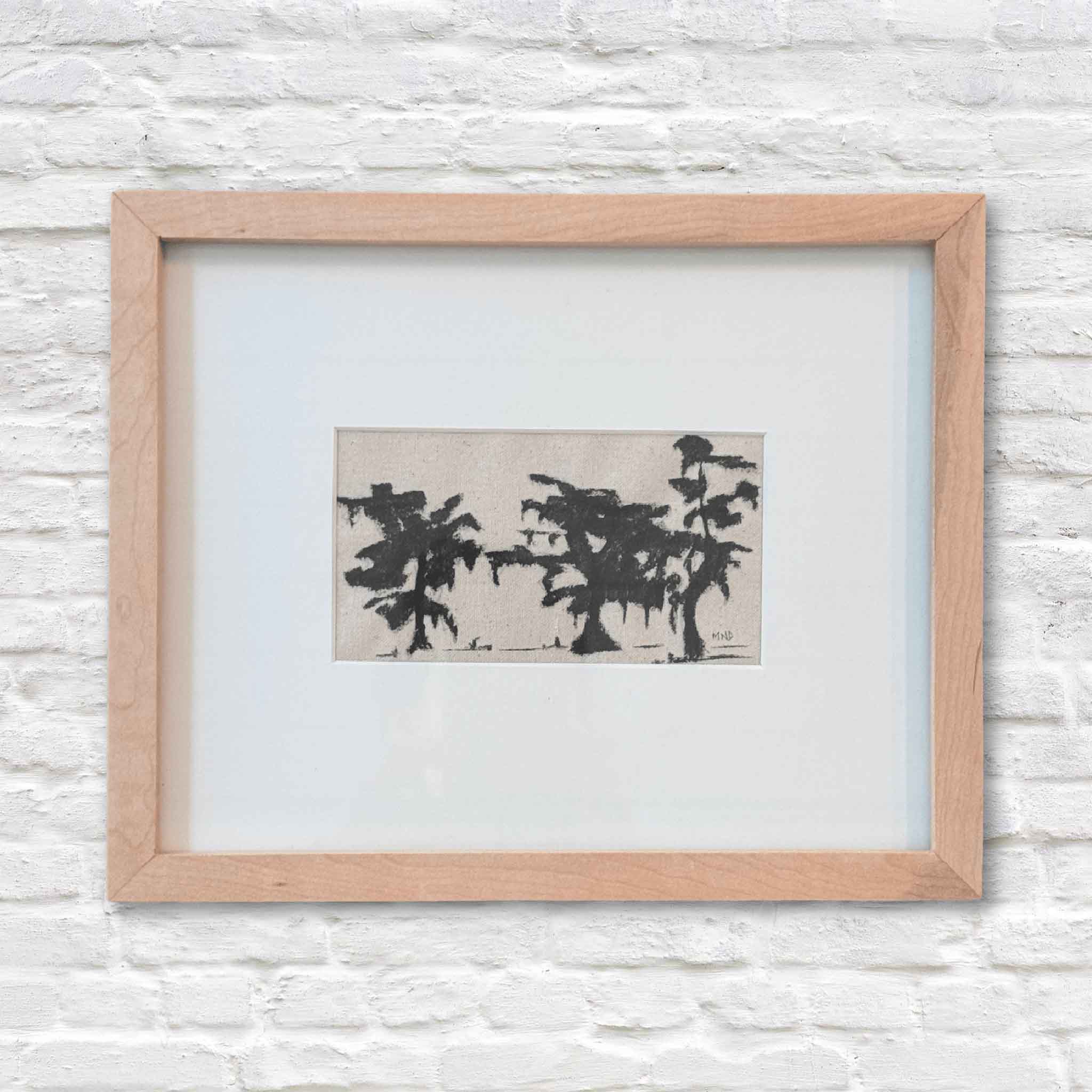 Framed abstract artwork of trees in ink on a textured white wall