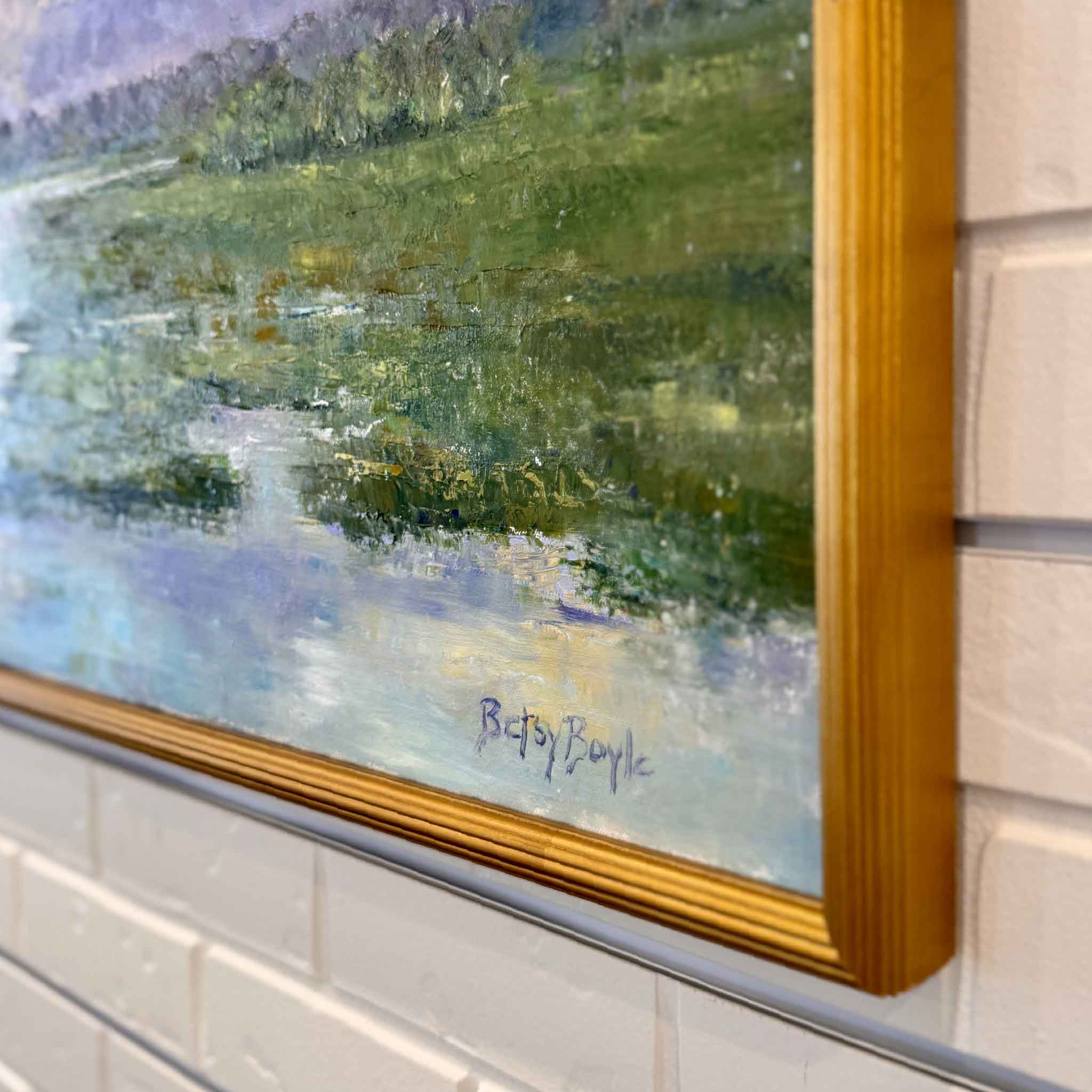 Framed painting of a marsh landscape with trees and water on a tiled wall.