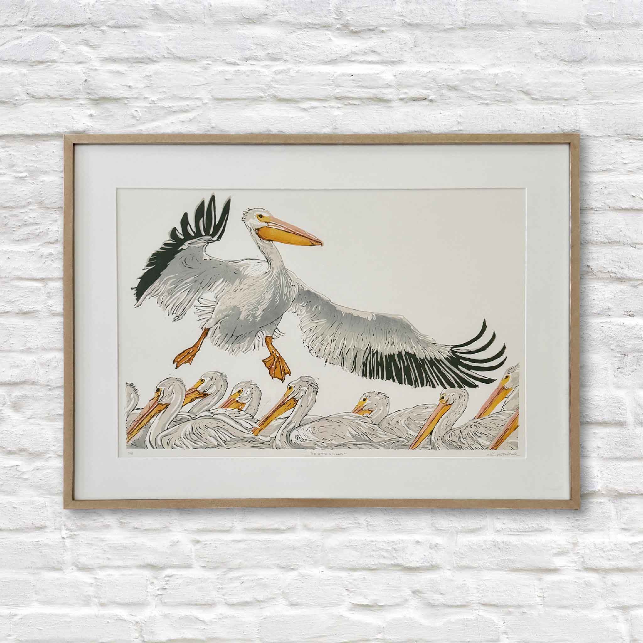 Original linocut reduction print The White Pelicans by Laurie McIntosh, featuring pelicans in flight and water, printed on cotton paper with layered “suicide printing” technique, framed in Laurie’s signature frame.