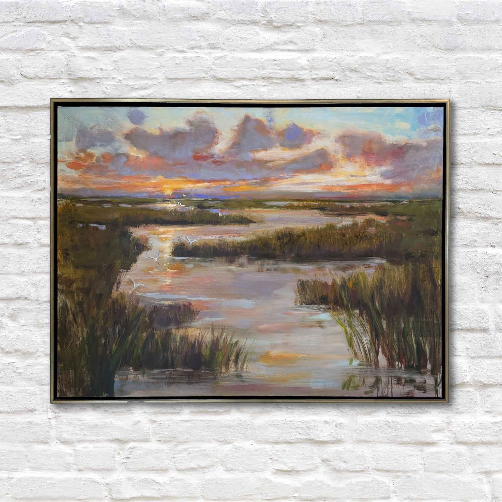 gold framed oil painting of lowcountry marsh at sunset on white brick wall
