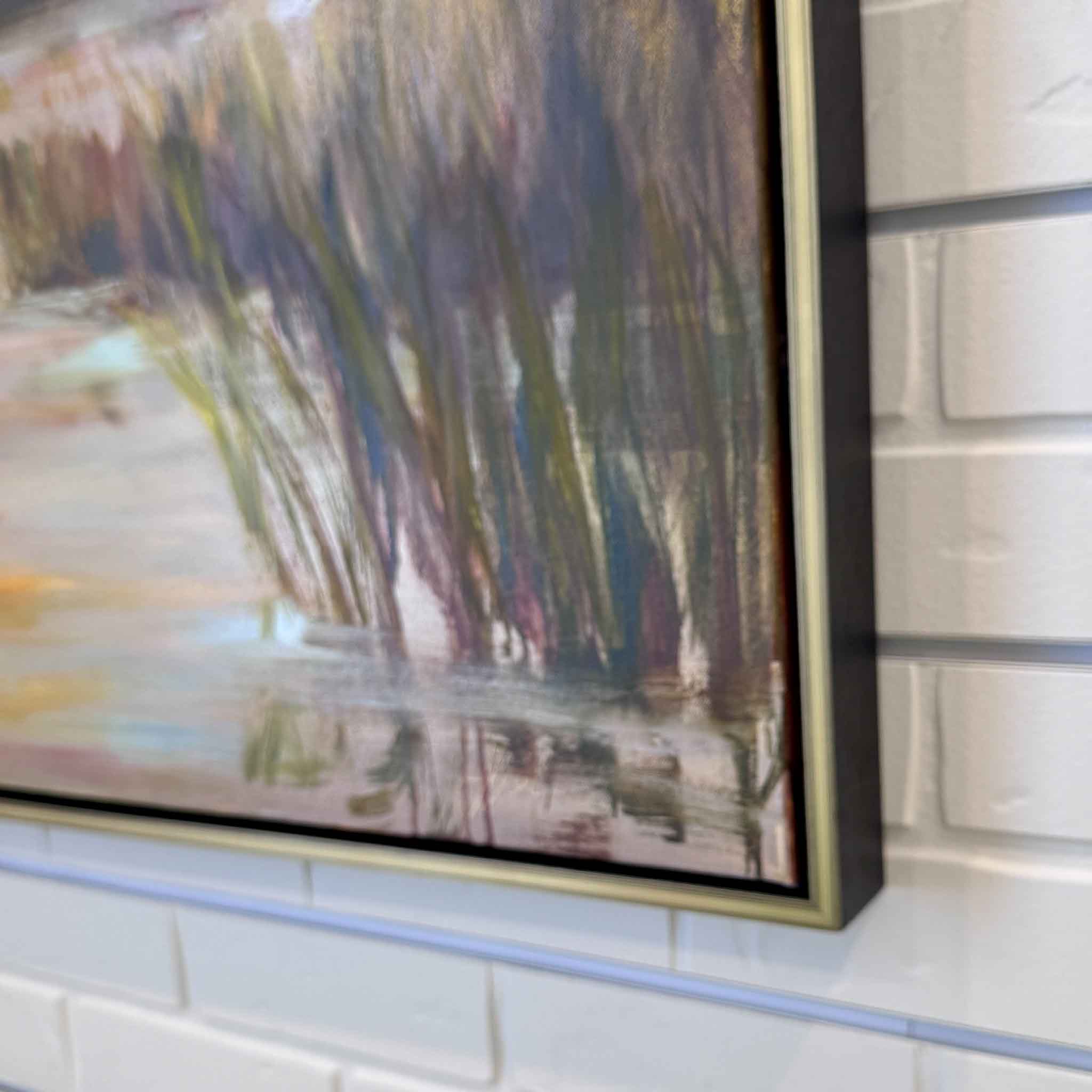 gold framed oil painting of lowcountry marsh at sunset on white brick wall