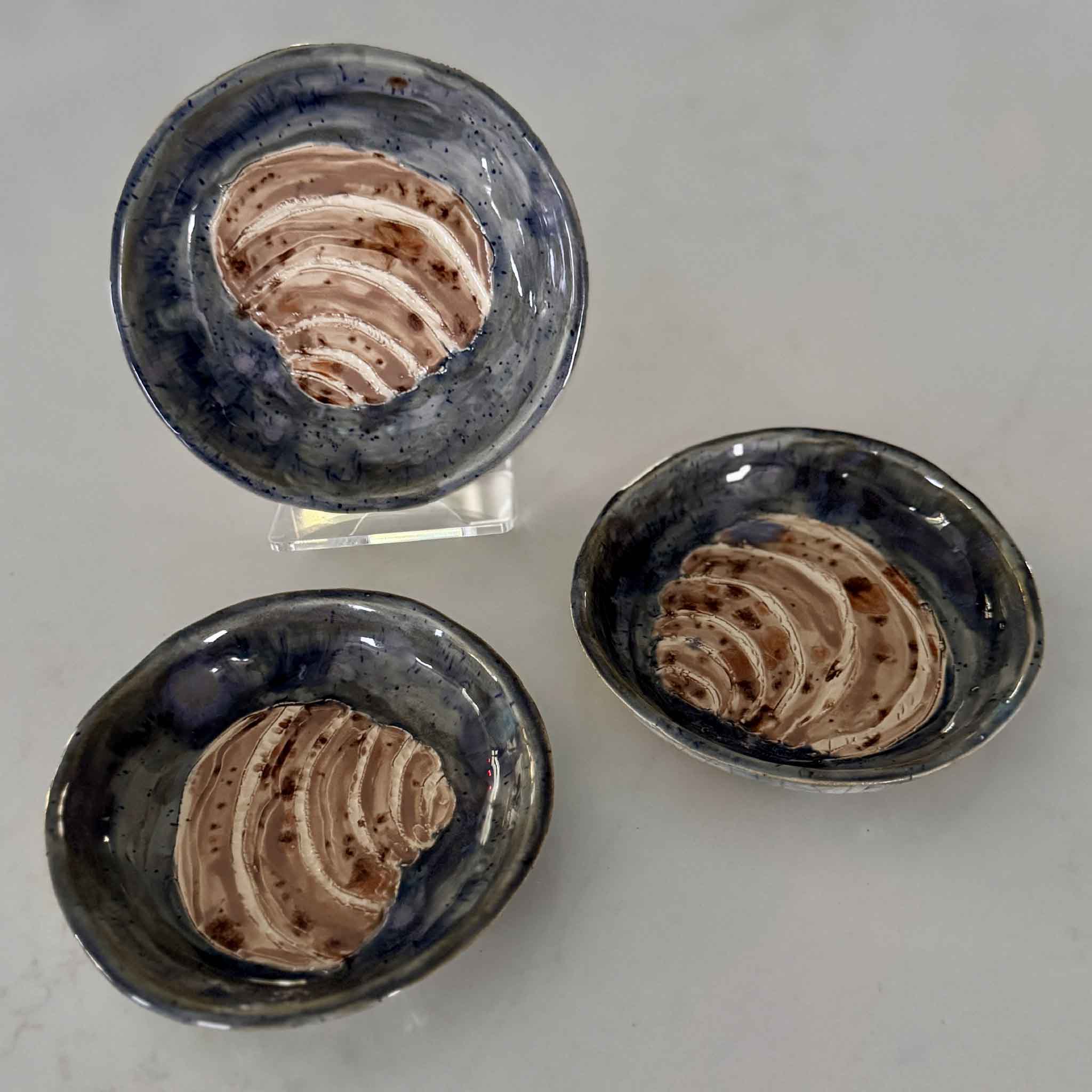 Three ceramic bowls with a textured interior on a light gray background