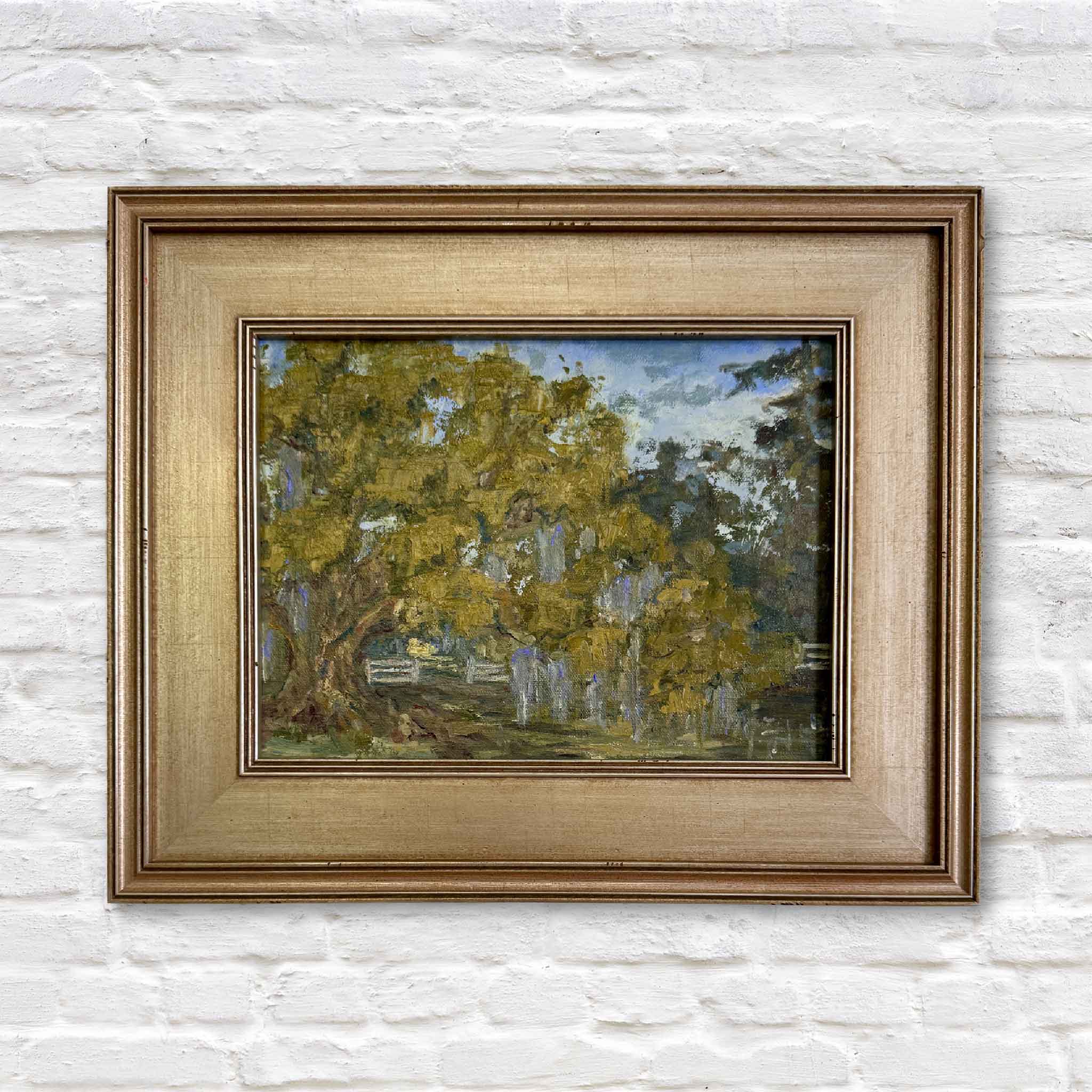 Original oil painting of the lowcountry in a gold frame against a white brick wall