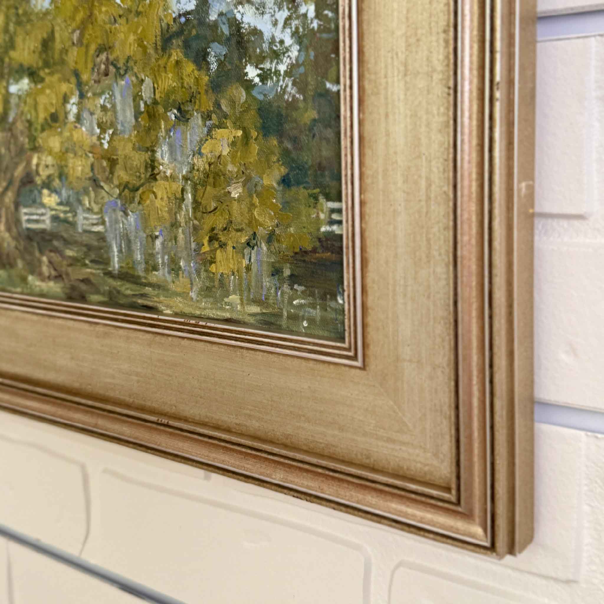 Original oil painting of the lowcountry in a gold frame against a white brick wall