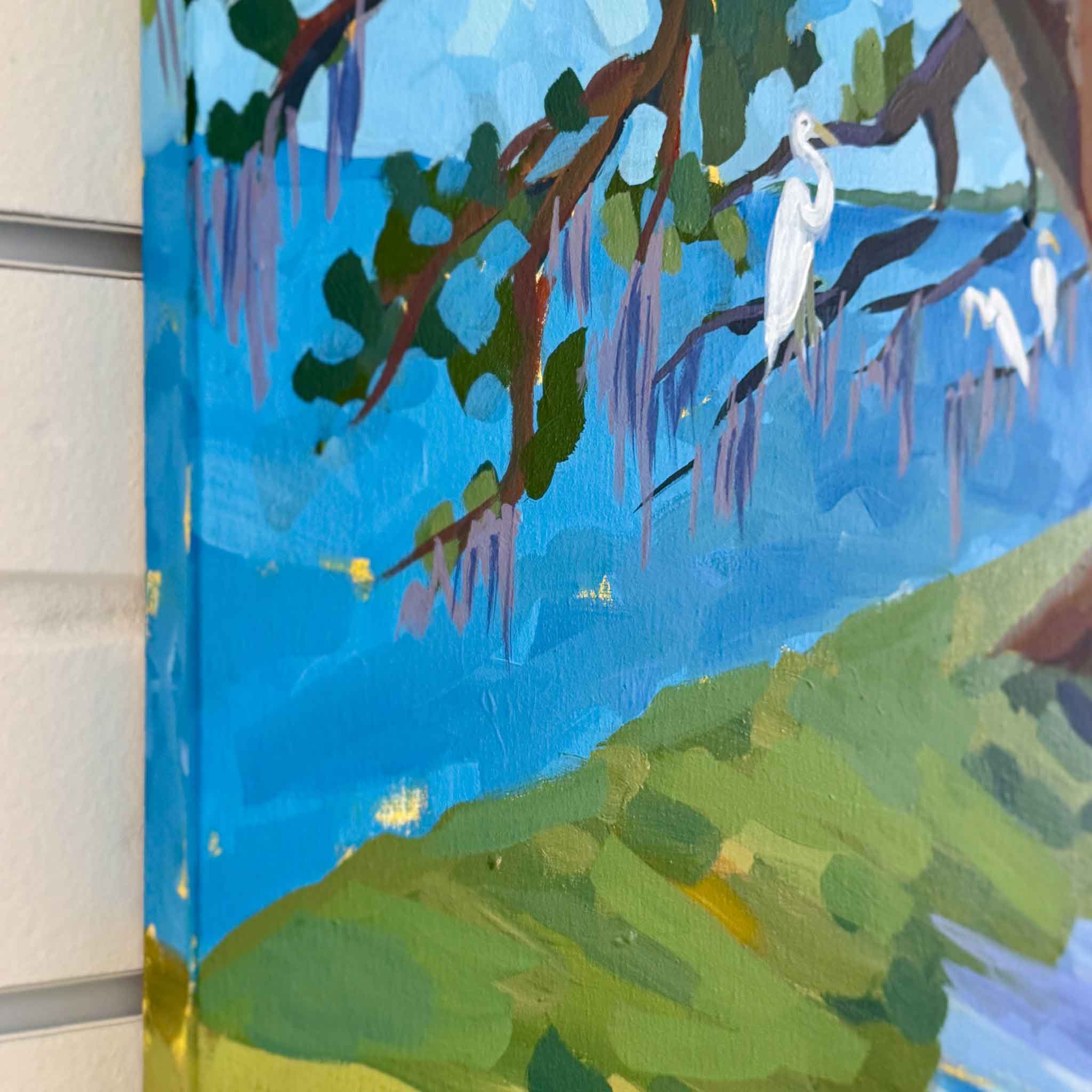Colorful mixed media artwork of lowcountry trees and water against a white brick wall