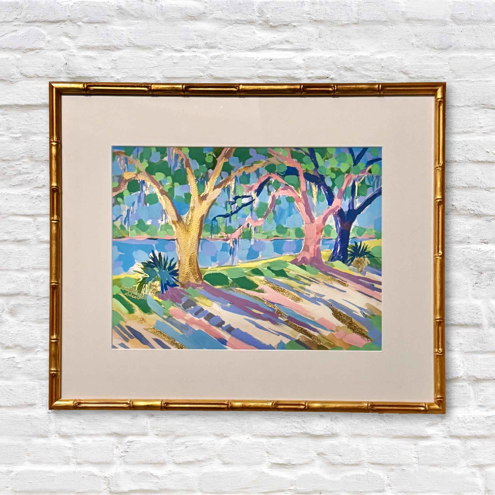 Bamboo gold framed mixed media artwork of colorful lowcountry trees on a white brick wall