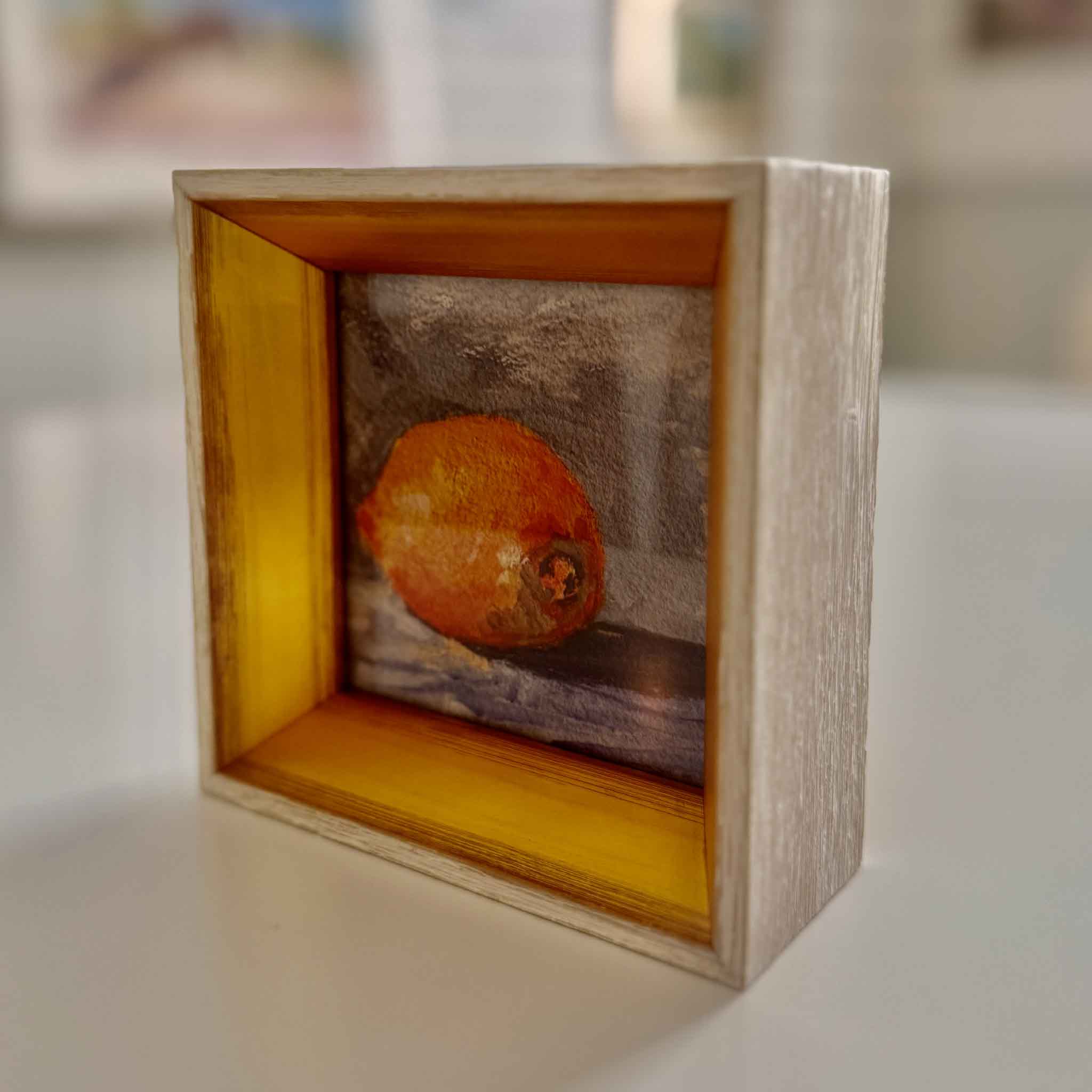 Small wooden frame with a textured lemon inside on a blurred background