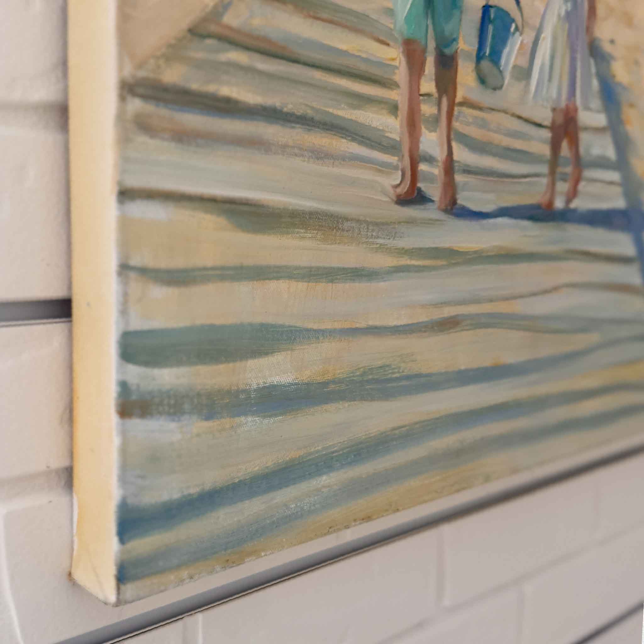 Framed painting of two people walking on a beach with a blue bucket.