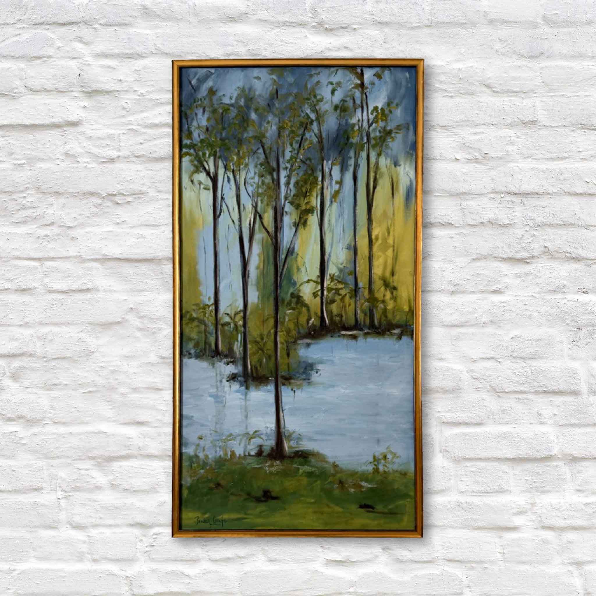 Framed painting of a forest scene with trees and water on a white brick wall.