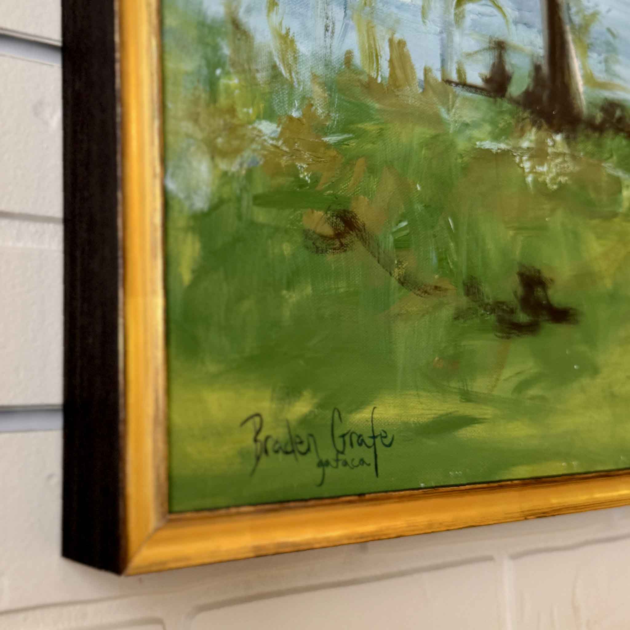 Framed painting with a signature on a white wall