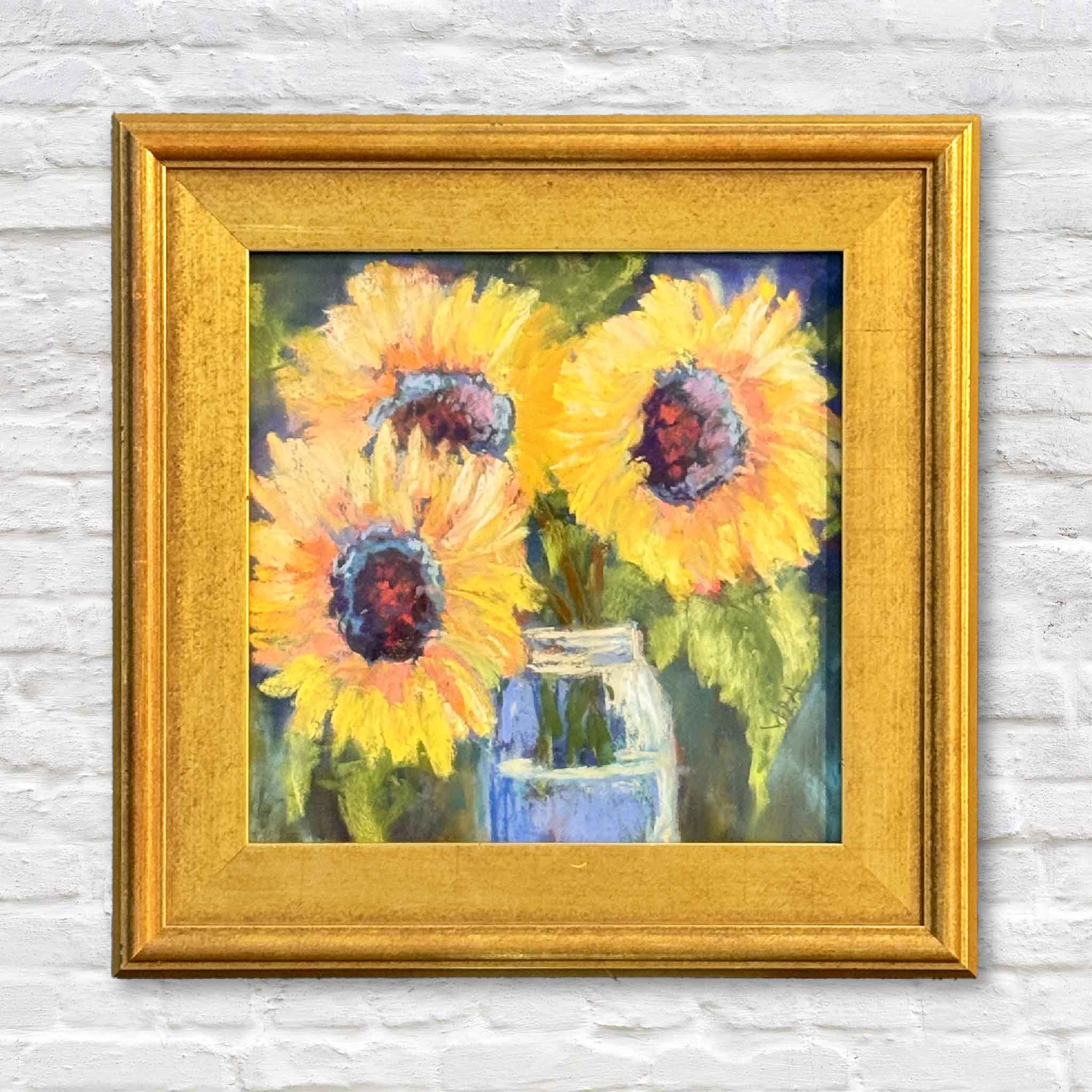 Framed painting of sunflowers on a white brick wall