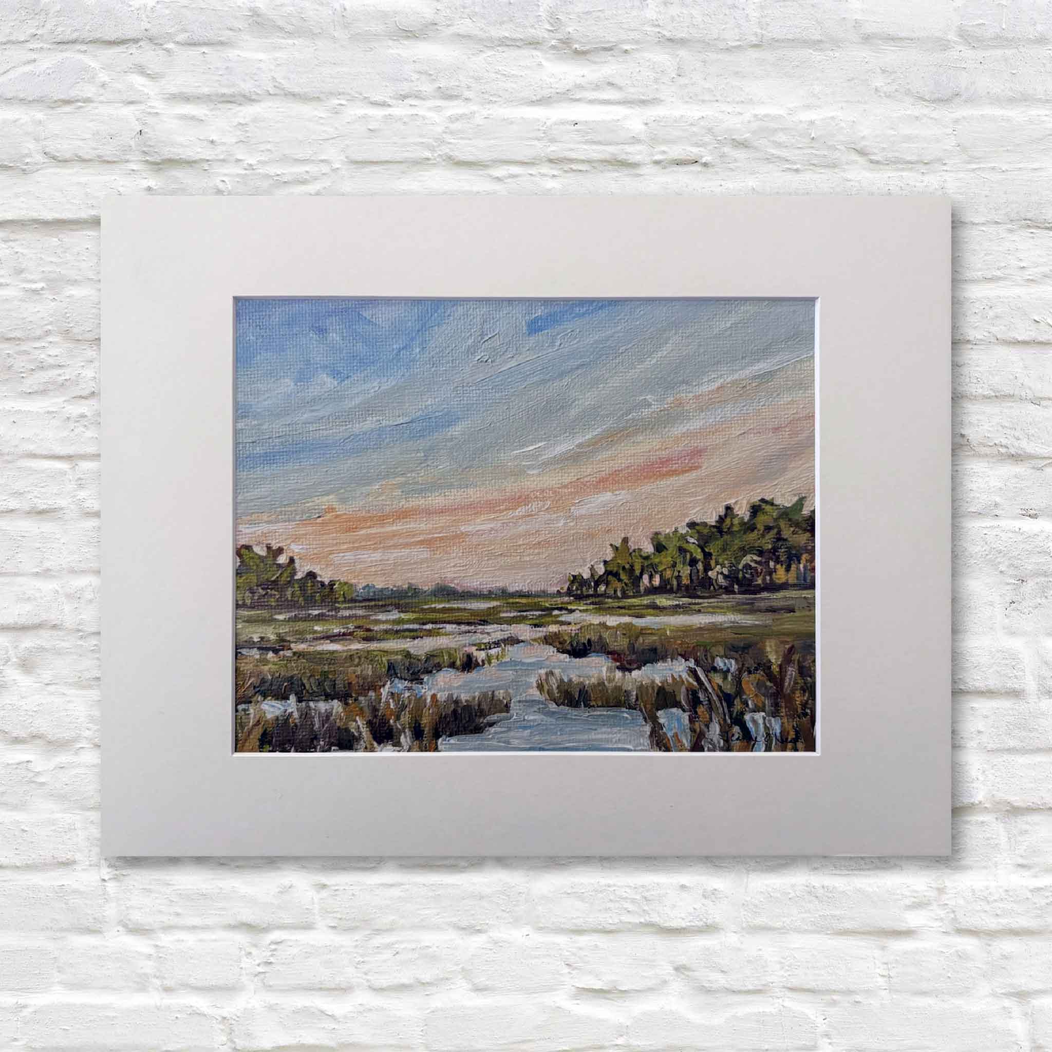 matted painting of a lowcountry marsh landscape with trees and water on a white brick wall.