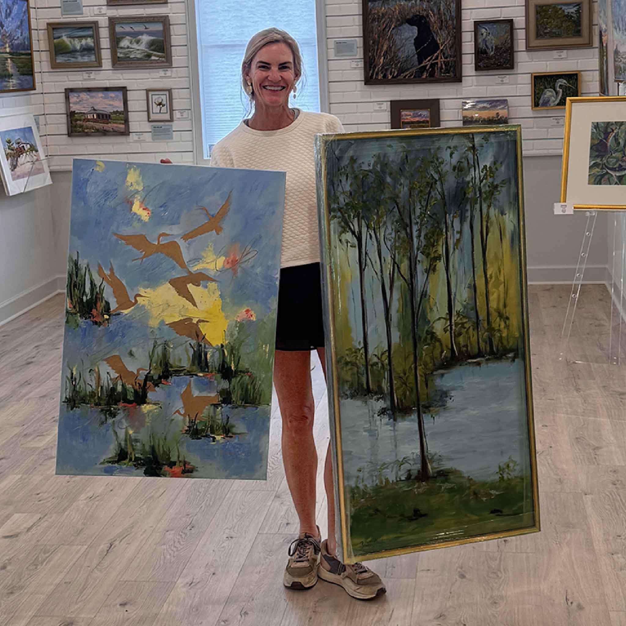 artist Braden Grafe holding two paintings at Gray Man Gallery.