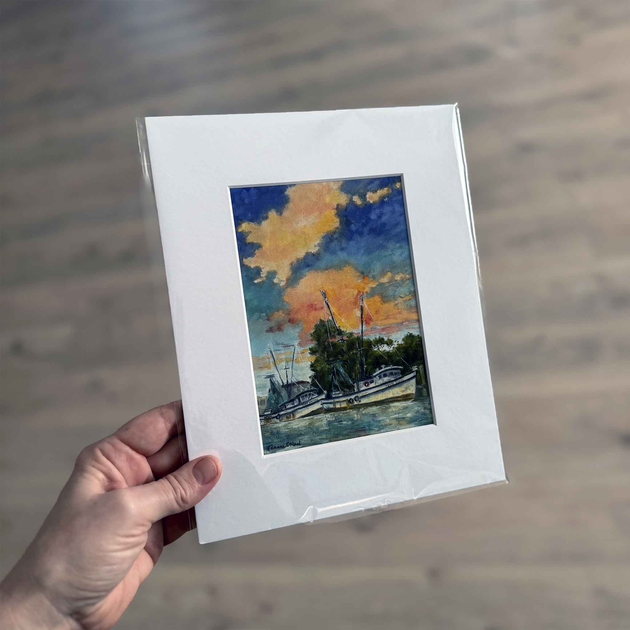 Matted 8x10 art print of Day’s End by Jeanne O’Neal, featuring shrimp boats docked along the water beneath a vivid Lowcountry sunset sky.