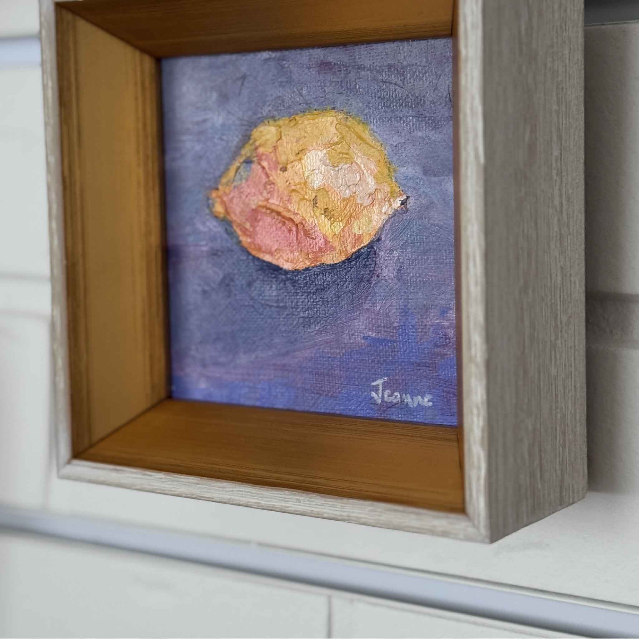 Framed painting of a textured round shape on a blue background