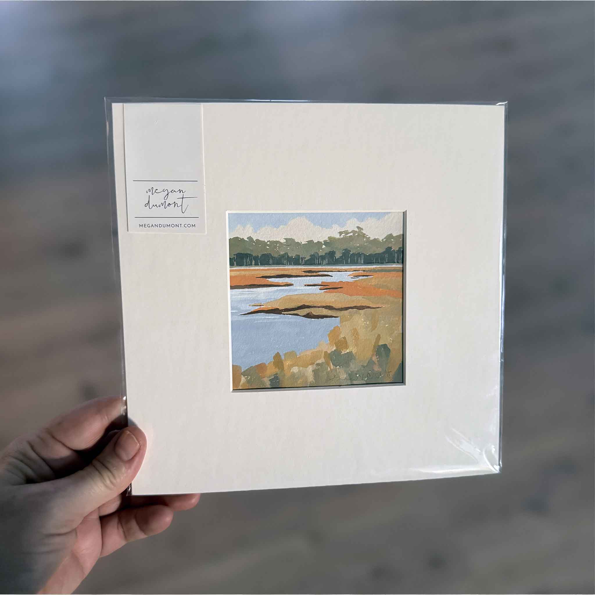 Original 8×8 gouache painting of North Inlet by Megan DuMont. A serene Lowcountry marsh scene matted to fit a standard 8×8 frame. Shop this local artwork today. Pictured at Gray Man Gallery.