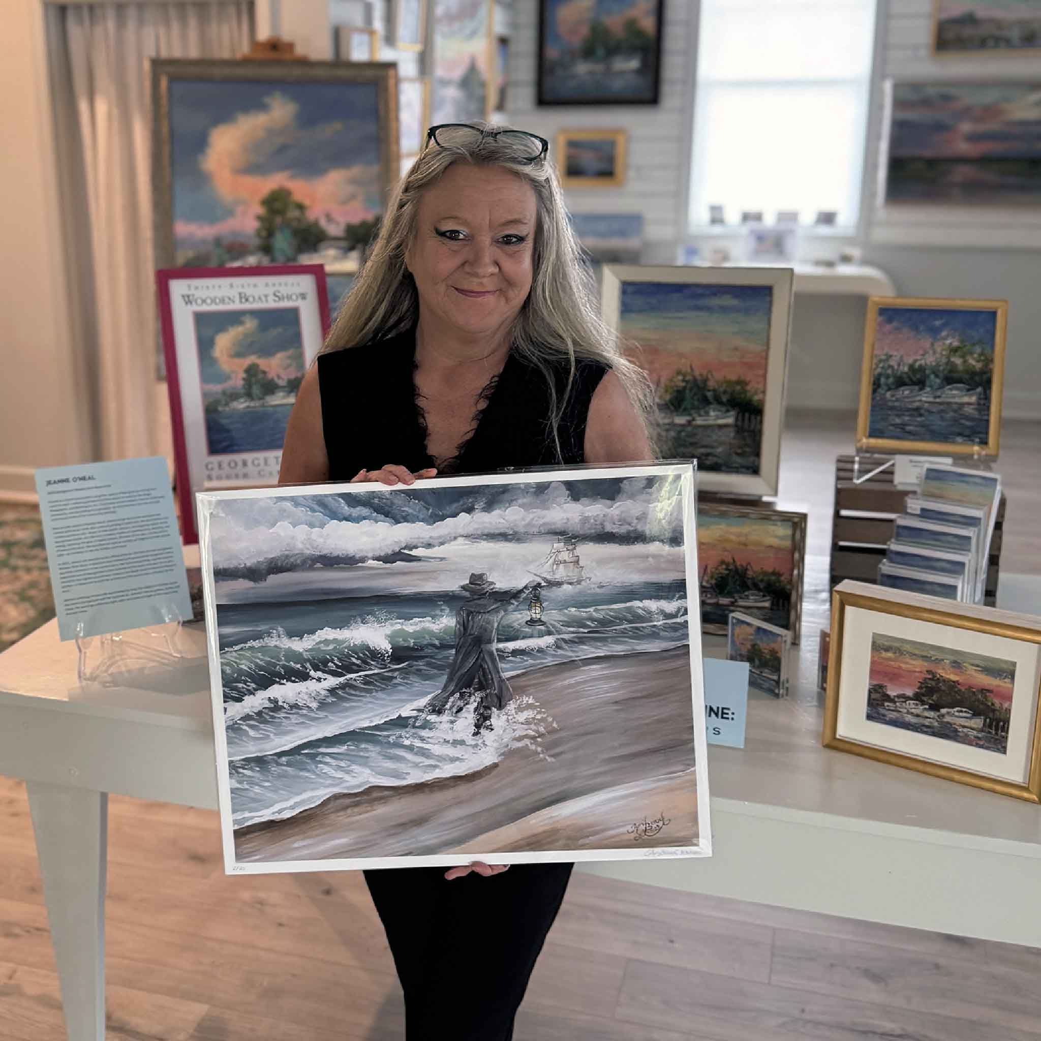 Signed and numbered fine art print of The Gray Man by April Bensch, depicting Pawleys Island’s ghostly guardian on the shoreline with lantern in hand as storm clouds gather. Pictured at Gray Man Gallery.