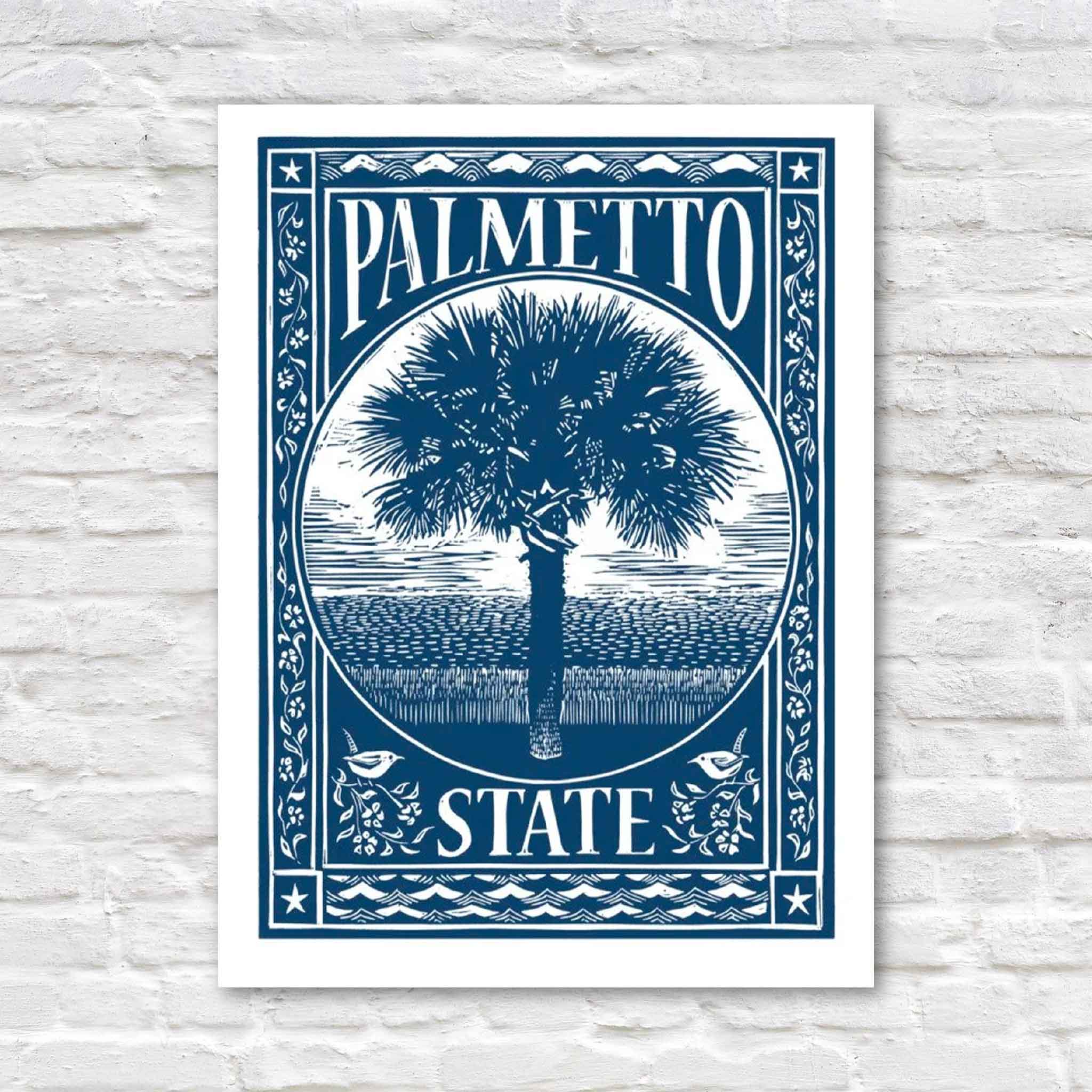Palmetto State linocut by Aaron Baldwin in blue, featuring South Carolina's iconic palmetto tree centered within an ornate decorative border overlooking a Lowcountry marsh. Original hand-pulled linocut available at Gray Man Gallery in Pawleys Island, South Carolina.