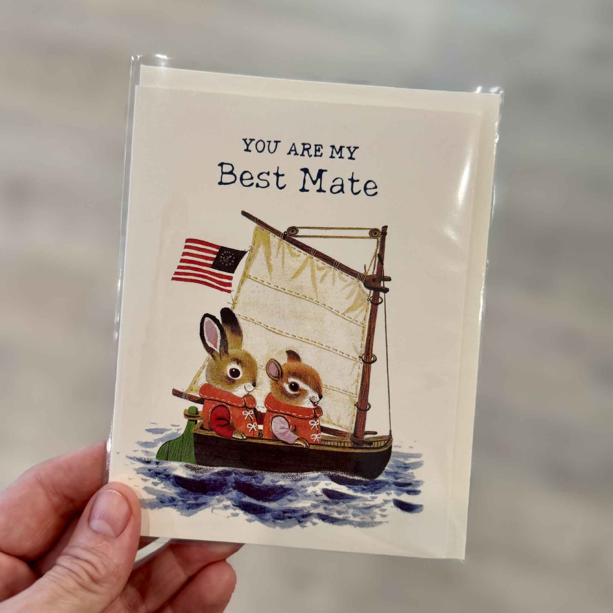 Best Mate greeting card featuring classic Richard Scarry Busytown artwork of two animal friends sailing a small boat together with the message "You Are My Best Mate." Photographed inside Gray Man Gallery in Pawleys Island, South Carolina.