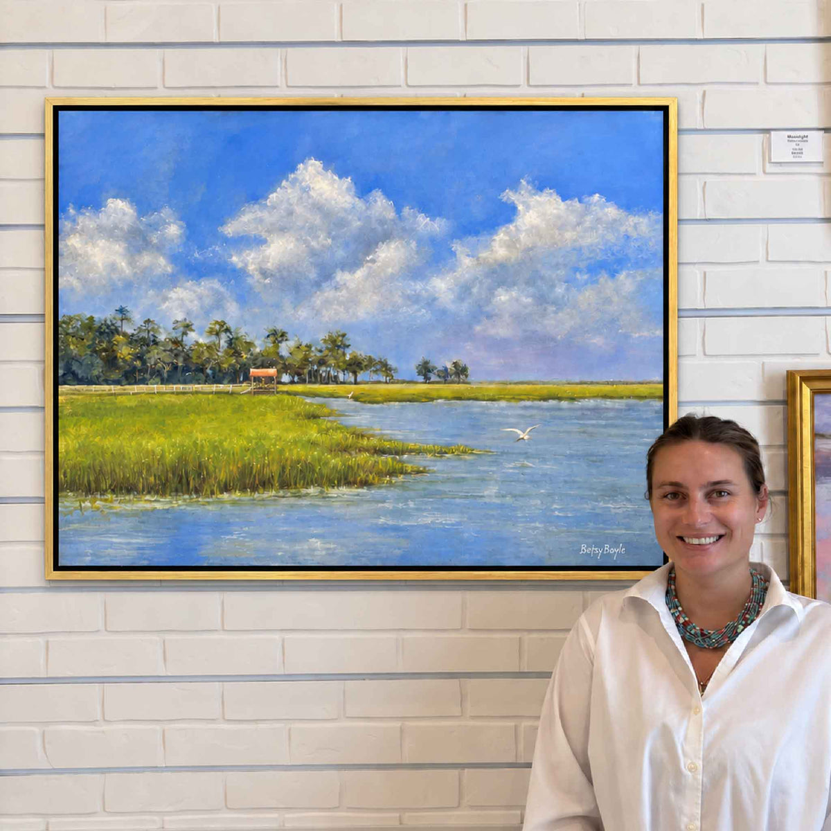 Blue and Green of Summer II by local South Carolina artist Betsy Boyle displayed at Gray Man Gallery in Pawleys Island, an original framed oil painting featuring vivid green coastal marsh, blue tidal water, soaring egret and dramatic summer clouds