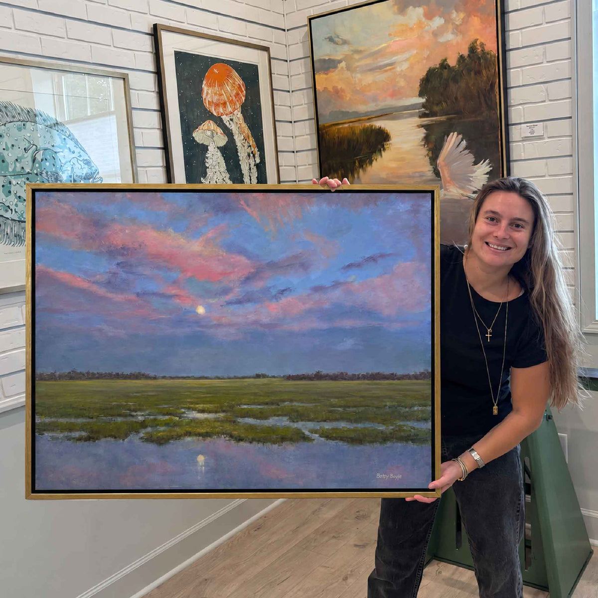 Cool Colors of Morning original Lowcountry marsh oil painting by South Carolina artist Betsy Boyle shown on display at Gray Man Gallery in Pawleys Island, with an expansive blue and pink morning sky, glowing moon and reflective tidal marsh