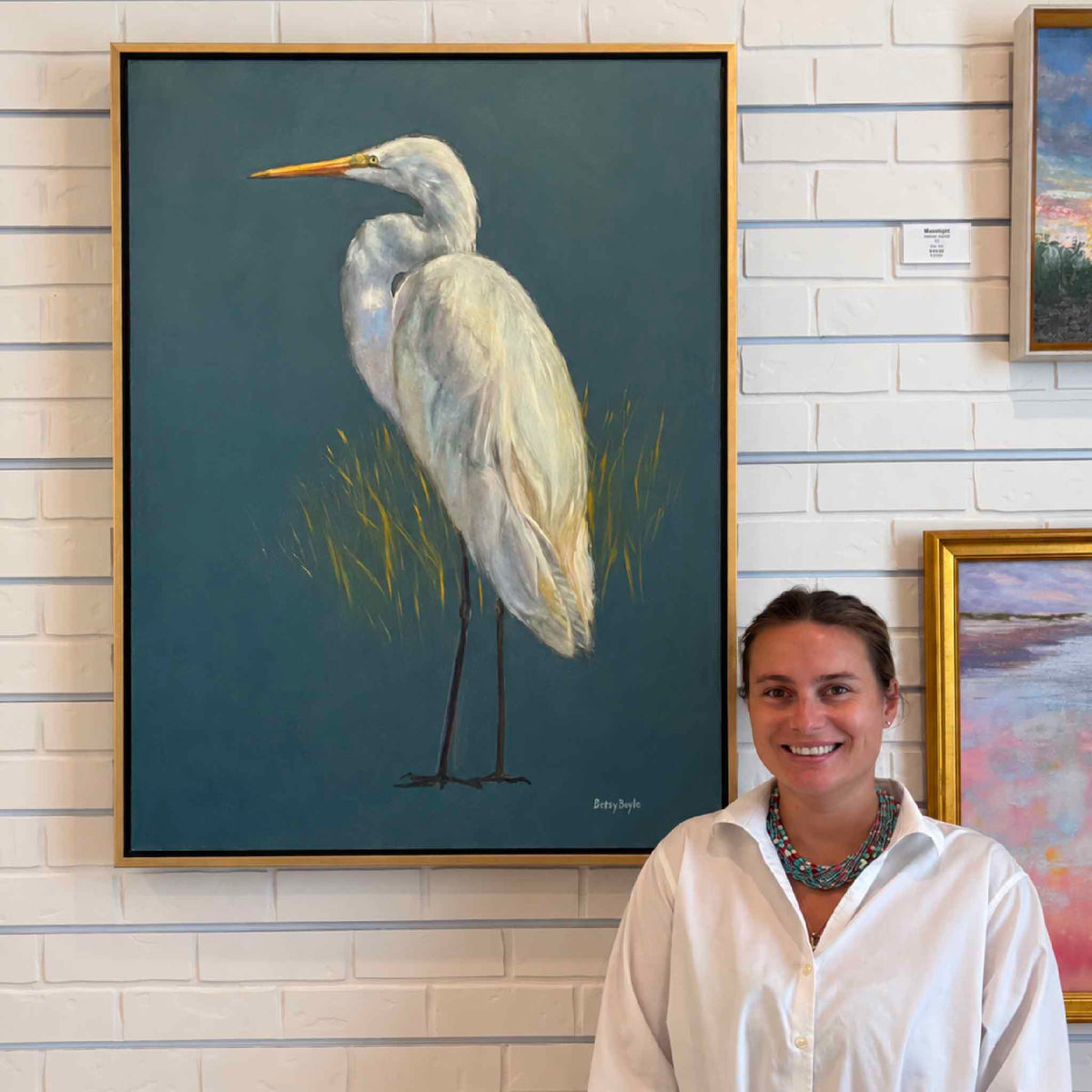 Proud original great egret oil painting by local South Carolina artist Betsy Boyle displayed at Gray Man Gallery in Pawleys Island, featuring a large white Lowcountry coastal bird portrait in a warm gold frame