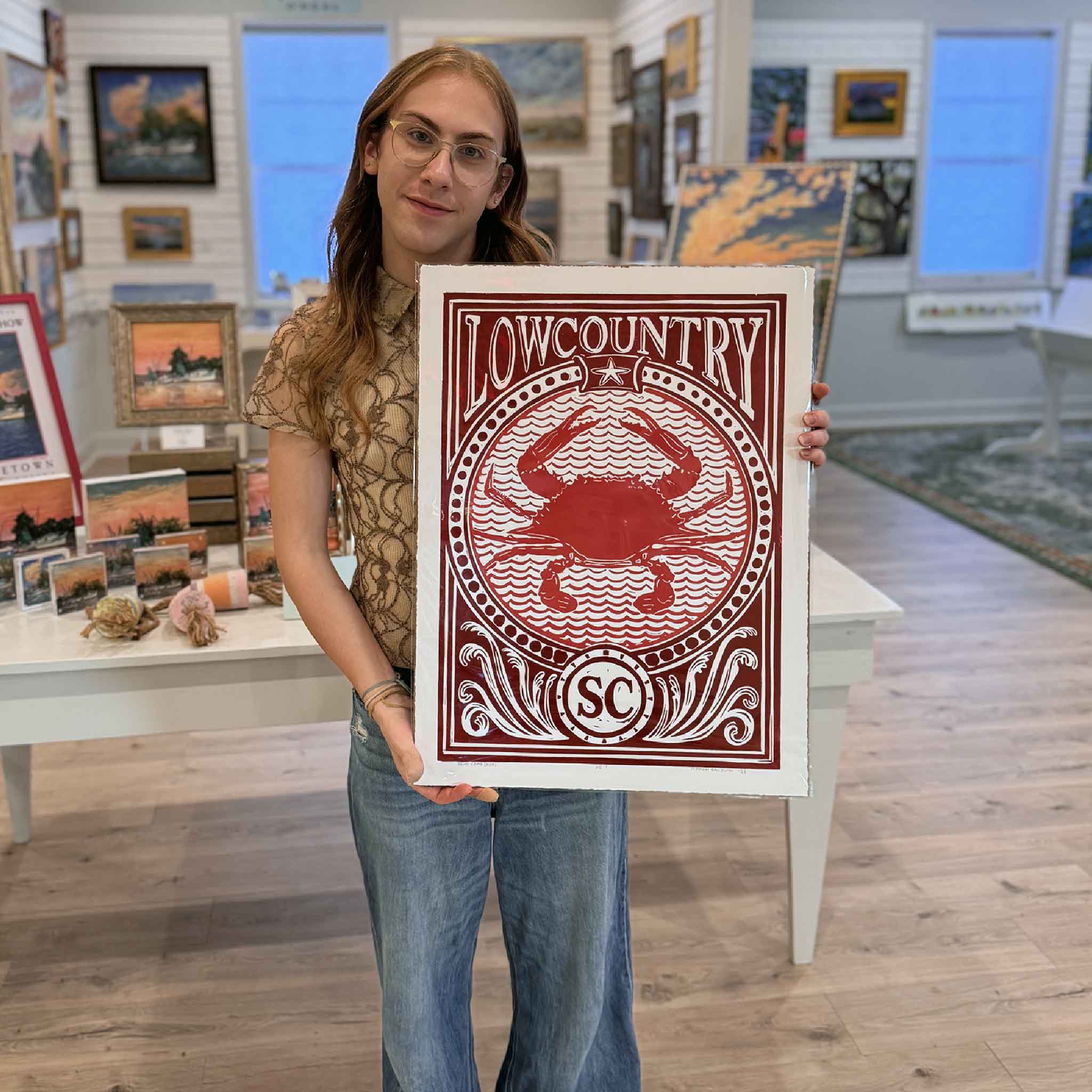 Alex holding the red Blue Crab linocut print by Aaron Baldwin at Gray Man Gallery.