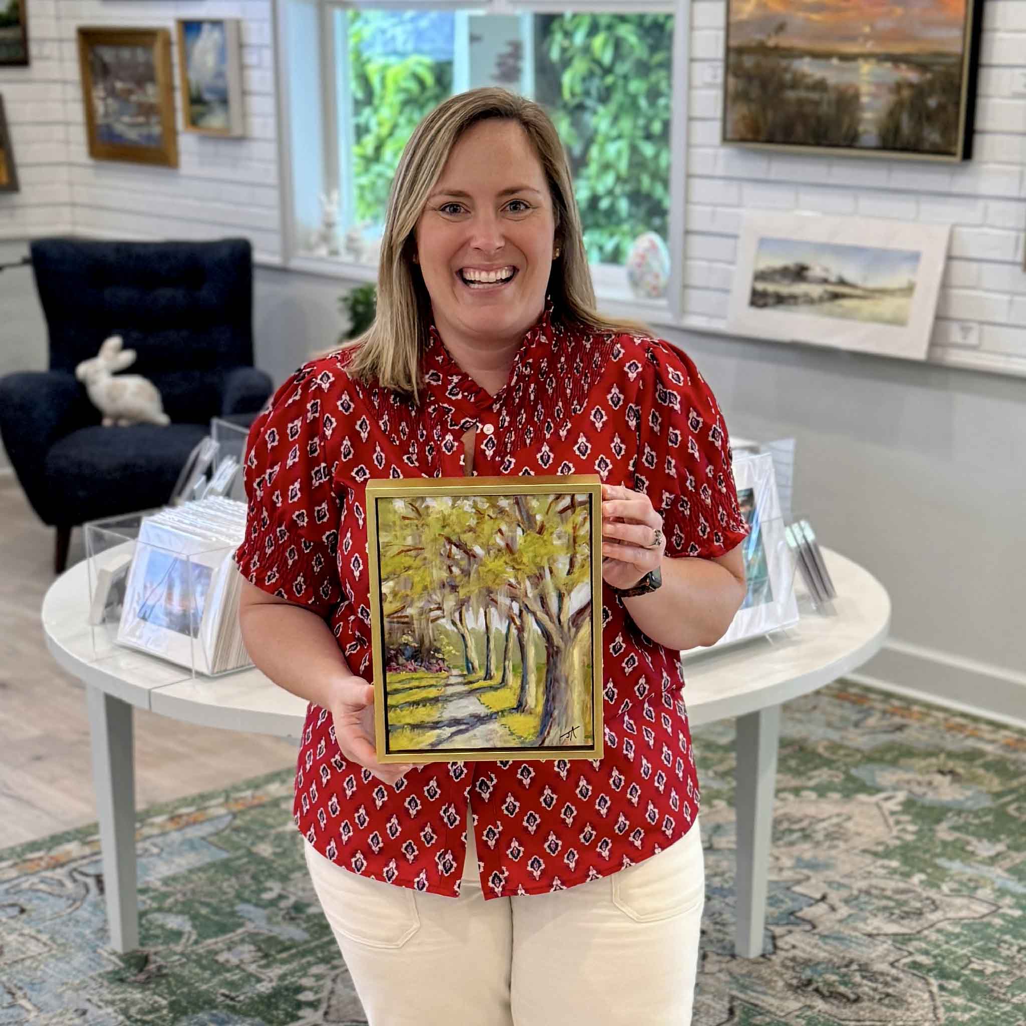 Bordy holding Along the Path by Jamie Arnold original oil painting created at Brookgreen Gardens inside Gray Man Gallery Pawleys Island showing scale of framed tree lined path landscape