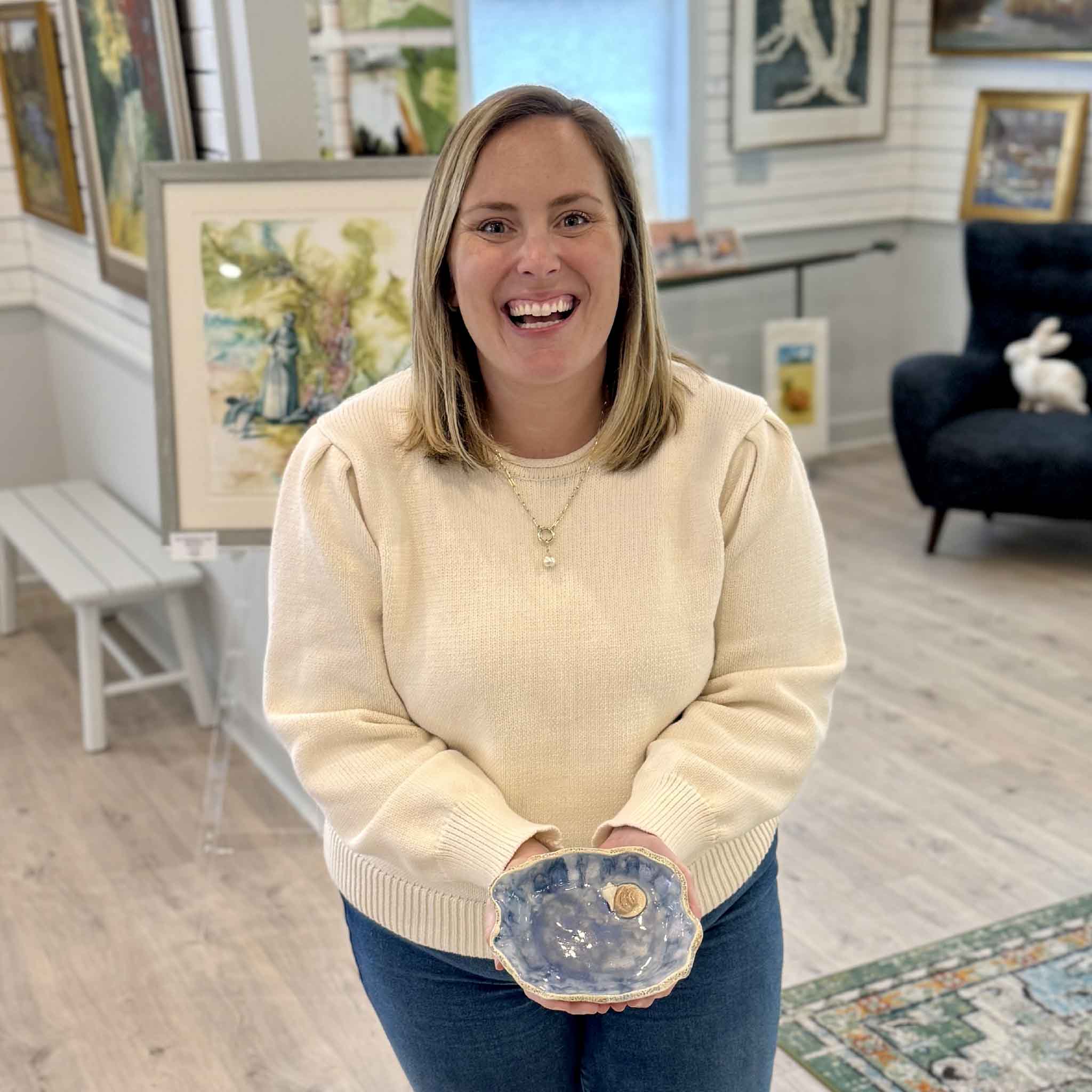Bordy holding Marsh Drift Bowl Blue Shell Study by local artist Vida Miller inside Gray Man Gallery Pawleys Island showing scale and layered coastal glaze