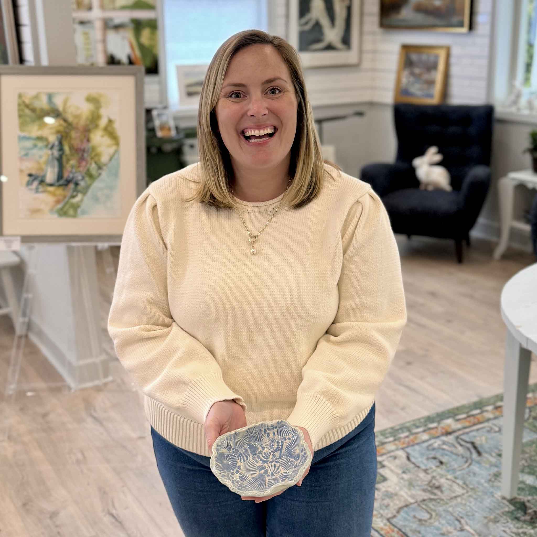 Bordy holding Pawleys Shore Shell Dish in Sea Glass Blue by local artist Vida Miller inside Gray Man Gallery showing scale and shell texture detail