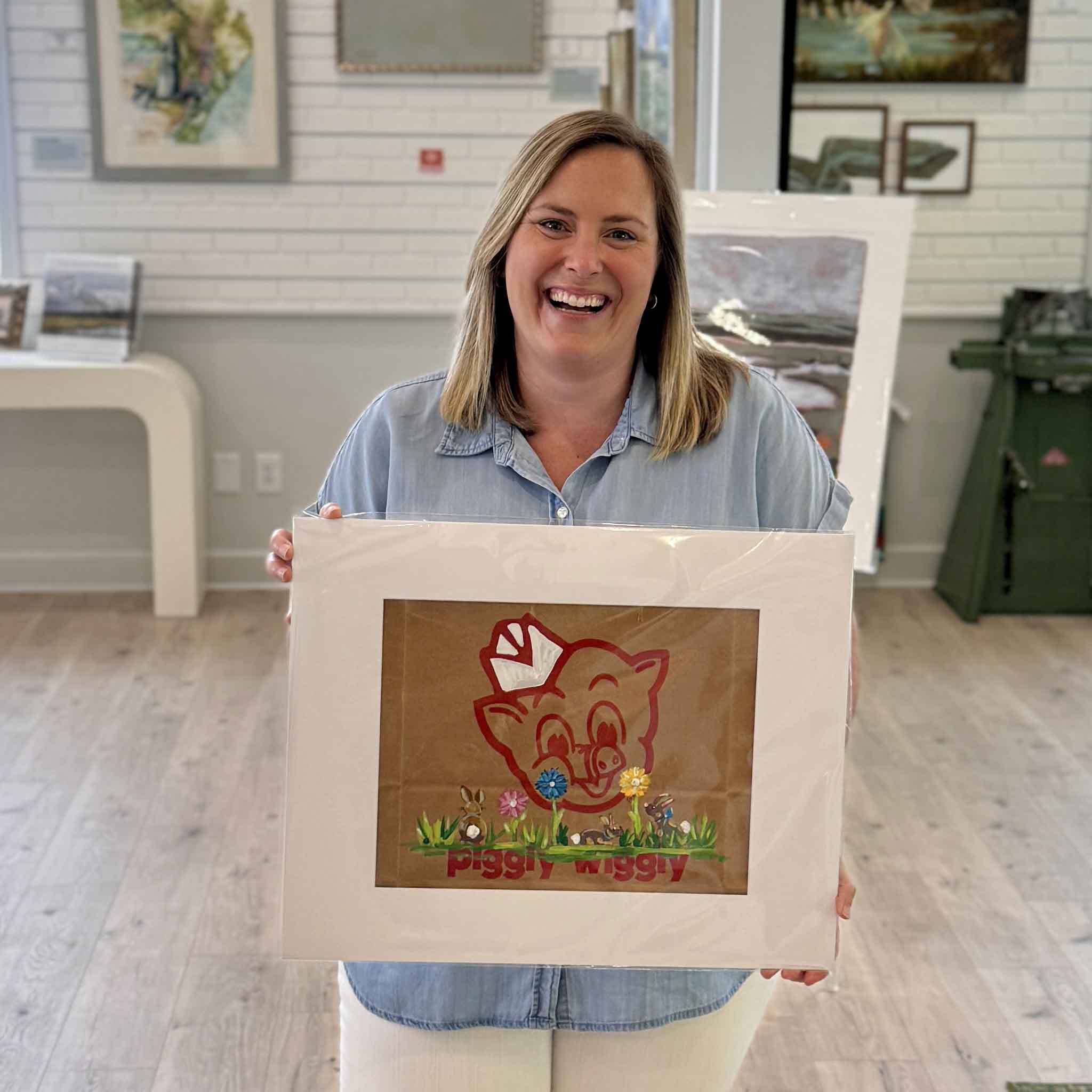 Bordy at Gray Man Gallery holding Piggly Wiggly Chocolate Bunnies painting by local artist Jenny Reynolds on an authentic grocery bag, showing size and detail