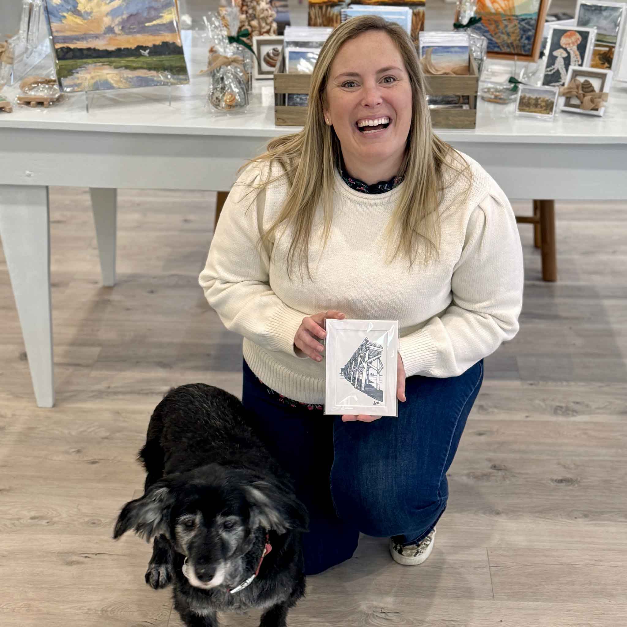 Bordy holding Pawleys Island Pier by Todd Halamka inside Gray Man Gallery. This professionally matted pen-and-ink coastal print celebrates the historic Pawleys Island Pier and is sized to fit a standard 5x7 frame without custom framing.