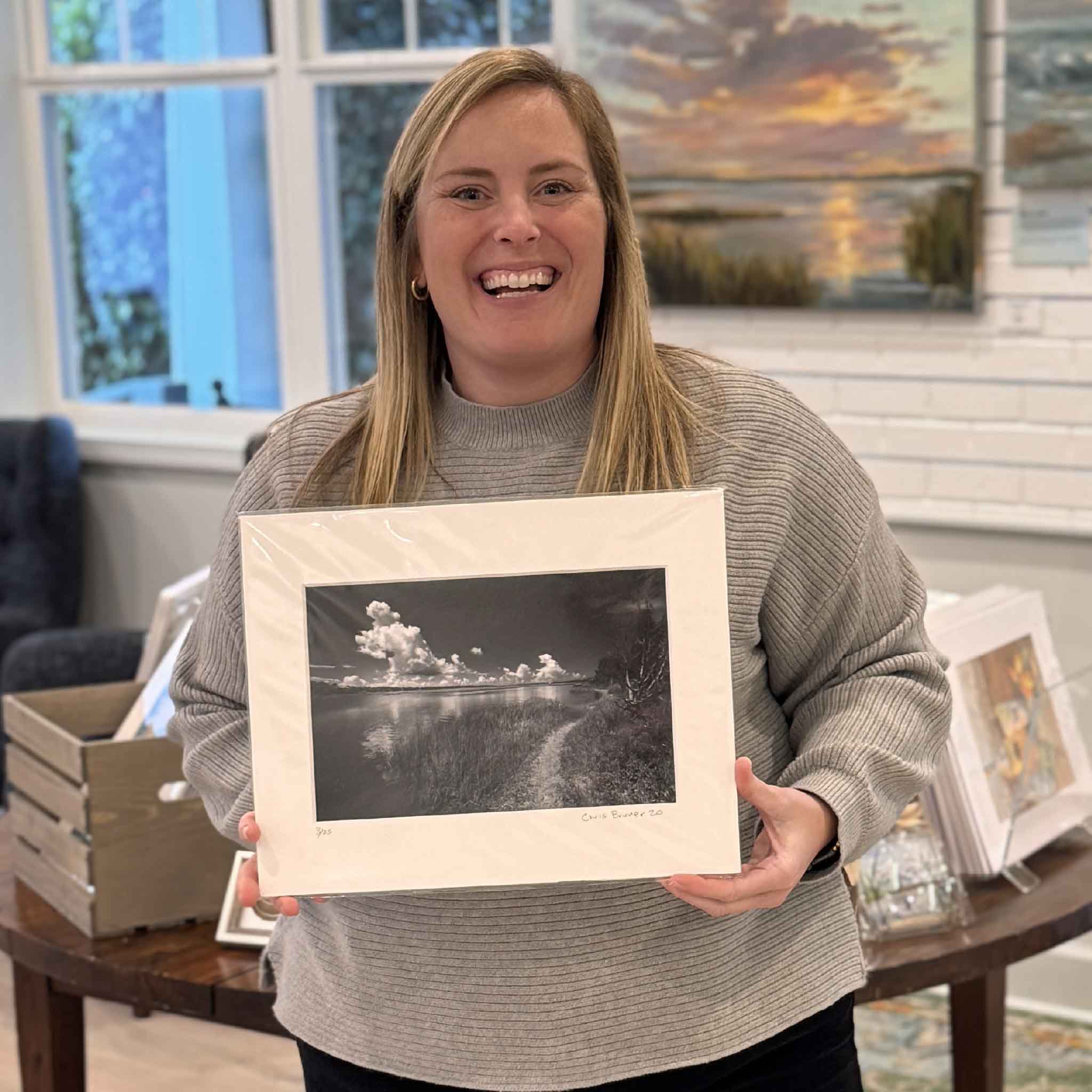 Gray Man Gallery team member holding Carolina #141 by local coastal photographer Chris Bruner, a black-and-white fine art photograph taken on Pawleys Island, South Carolina, professionally matted and available at Gray Man Gallery. 