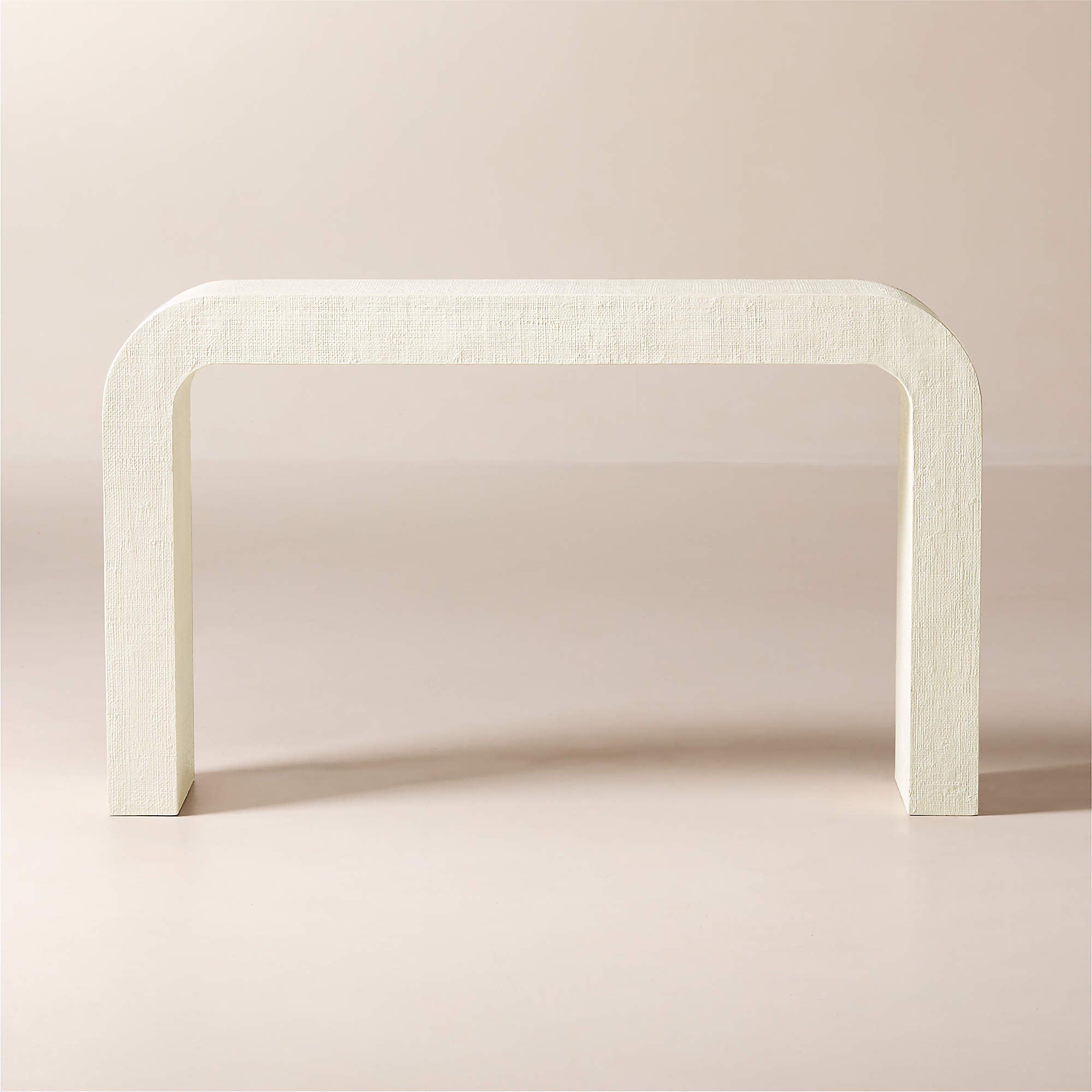 CB2 Crescent 52 inch ivory resin console table styled against neutral background highlighting sculptural waterfall form and textured finish suitable for modern coastal interiors
