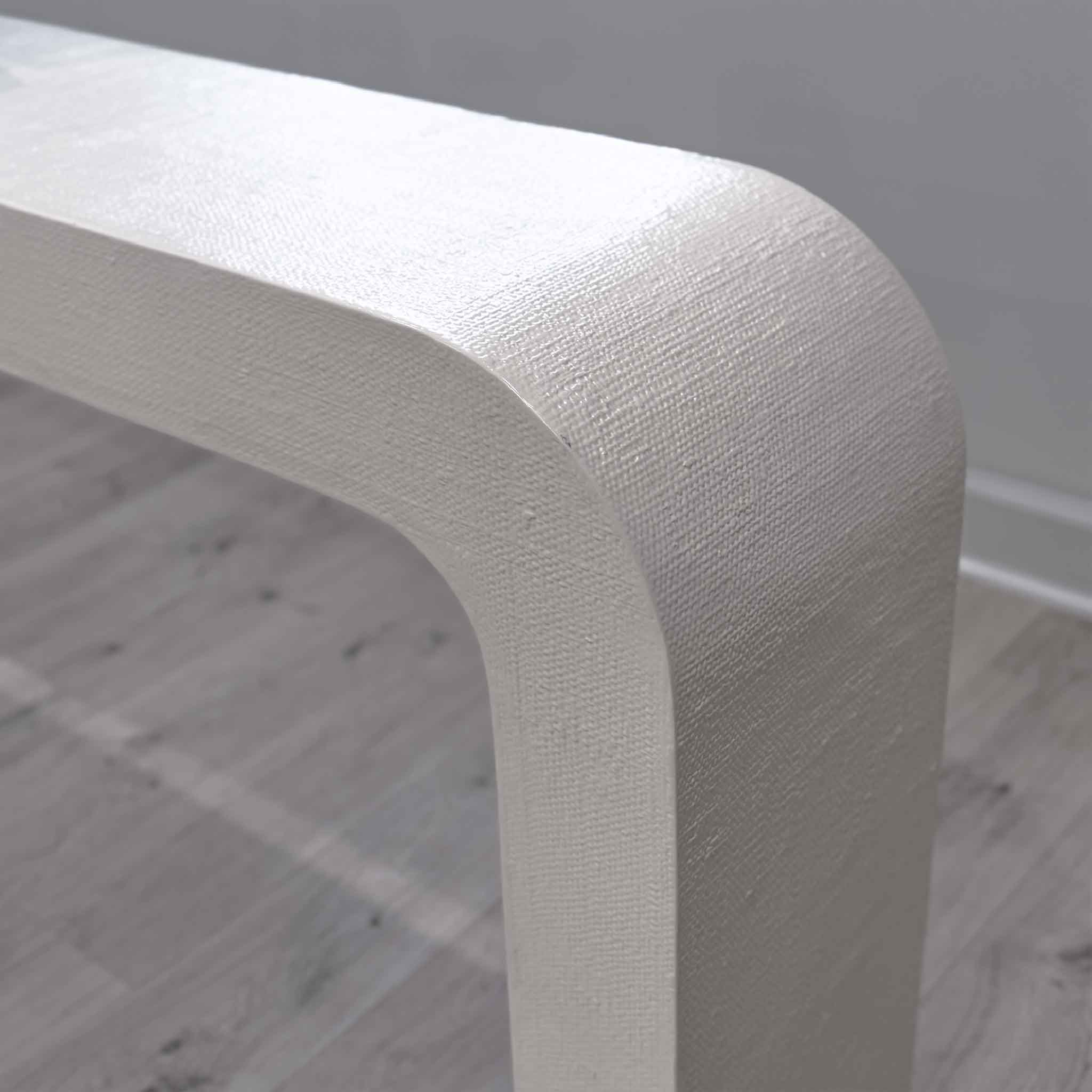 Closeup corner detail of CB2 Crescent ivory resin console table showing rounded waterfall edge and textured raffia inspired finish from gallery display piece