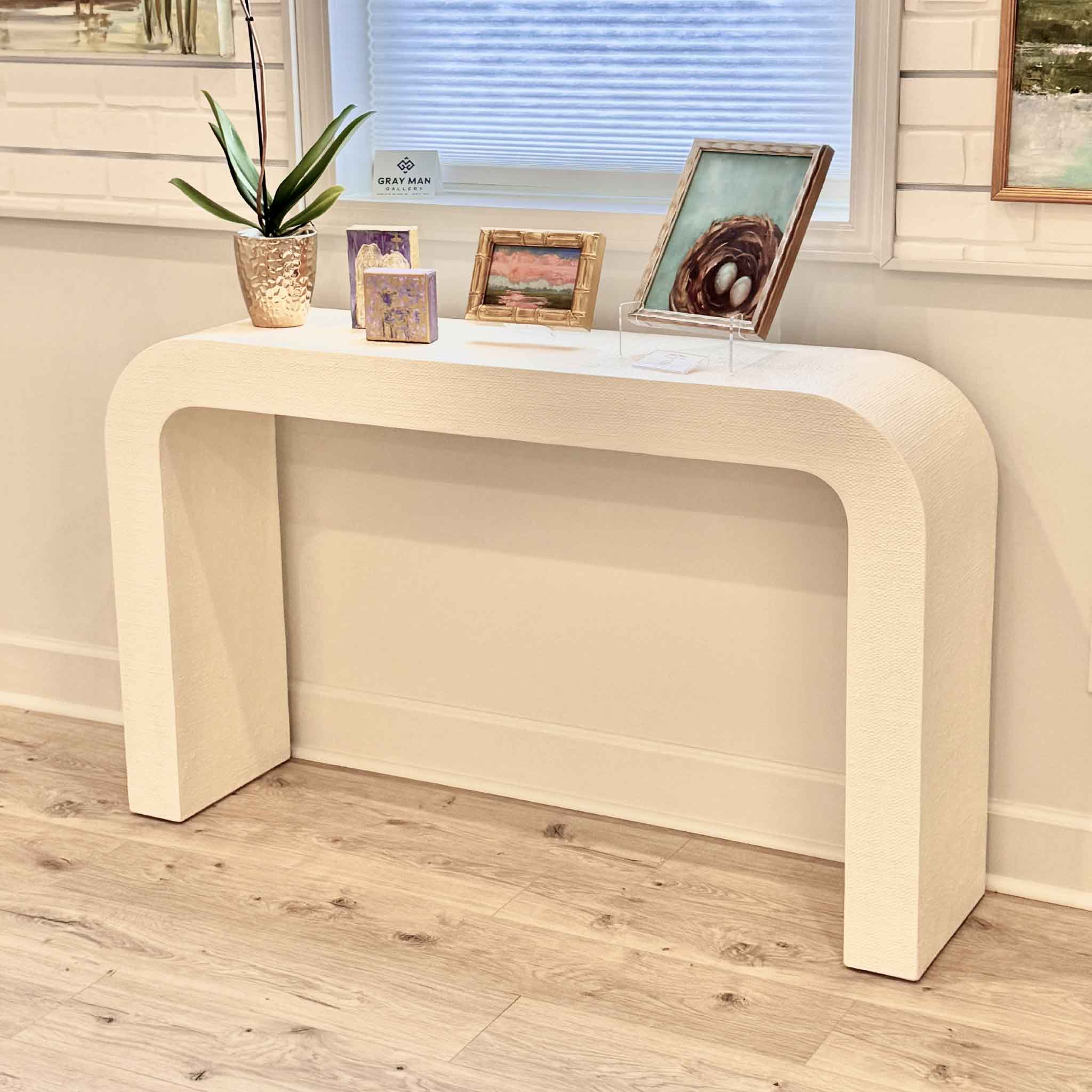 CB2 Crescent ivory resin console table styled inside Gray Man Gallery Pawleys Island with artwork and decor demonstrating scale versatility for coastal homes and entryways